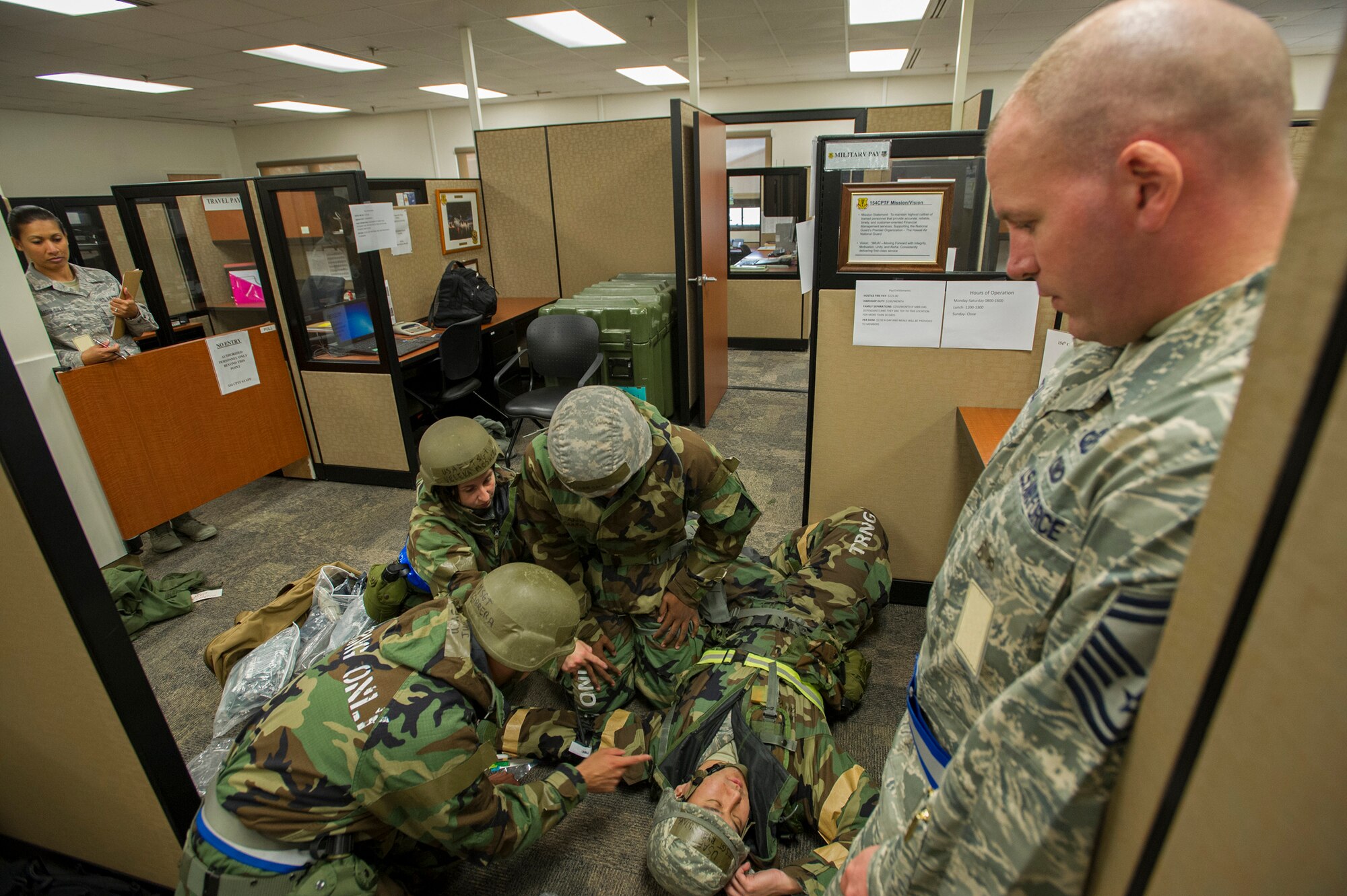 Members from 15th Comptroller Squadron and 154th Comptroller Flight demonstrate self-aid buddy care procedures on a downed Airman, as Tech. Sgt. Sue Murasrik-Quiles, 154th Comptroller Flight travel pay technician, left, and Senior Master Sgt. Patrick Seiler, 15th Comptroller Squadron superintendent, right, observe and evaluate their personnel at the military pay and finance building, during an Operational Readiness Inspection at Joint Base Pearl Harbor-Hickam, Hawaii, Nov. 7. 2013. (U.S. Air Force photo/Tech. Sgt. Jerome S. Tayborn)