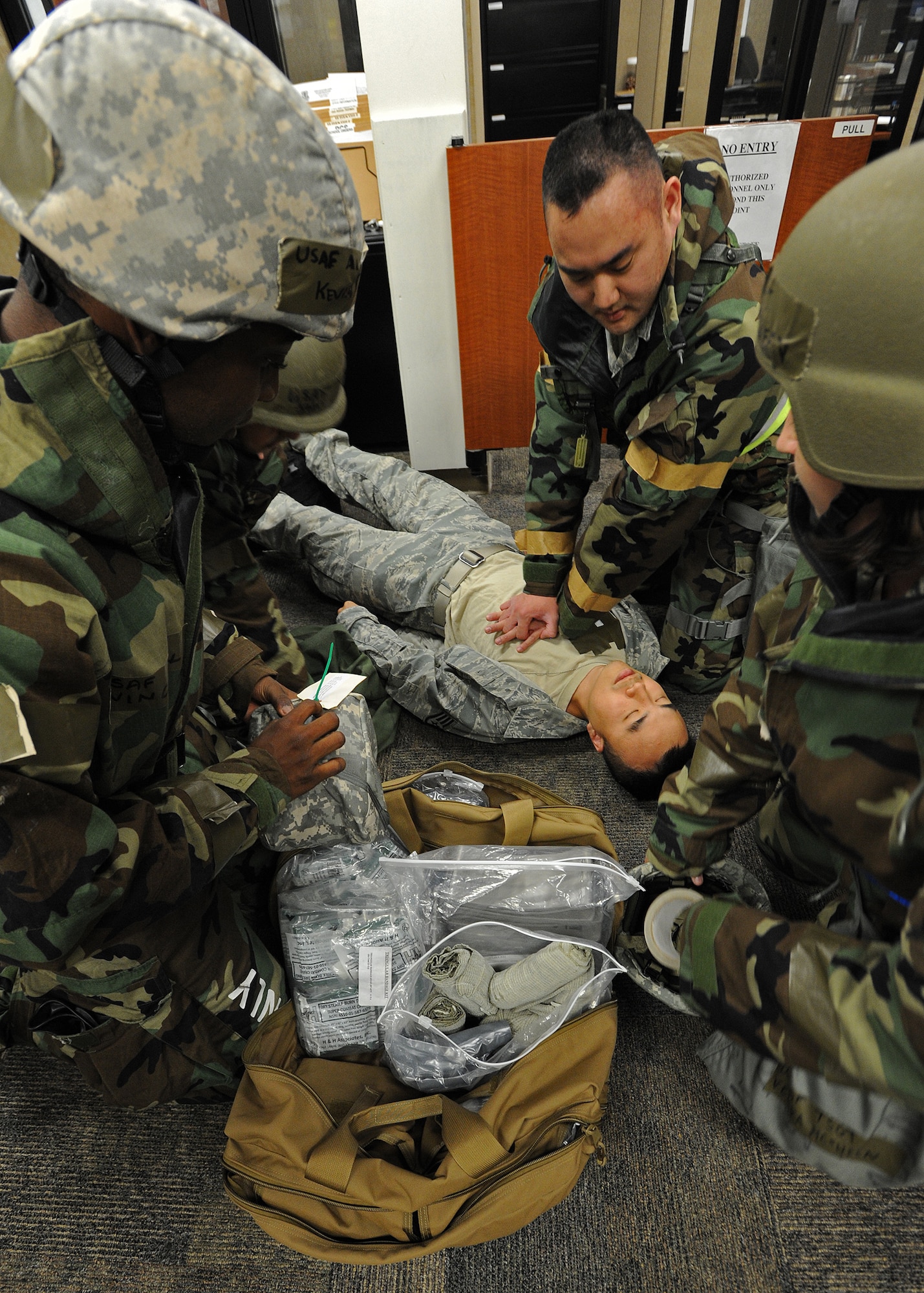 Tech. Sgt. Ryan Yung, 154th Comptroller Flight travel pay technician, top right, and members from the 15th Comptroller Squadron and 154th Comptroller Flight demonstrate self-aid buddy care procedures on a downed Airman at the military pay and finance building, during an Operational Readiness Inspection at Joint Base Pearl Harbor-Hickam, Hawaii, Nov. 7. 2013. Airmen are drilled on donning mission-oriented protective posture gear and surviving simulated chemical attacks in an austere environment while still proceeding with the mission. (U.S. Air Force photo/Tech. Sgt. Jerome S. Tayborn)