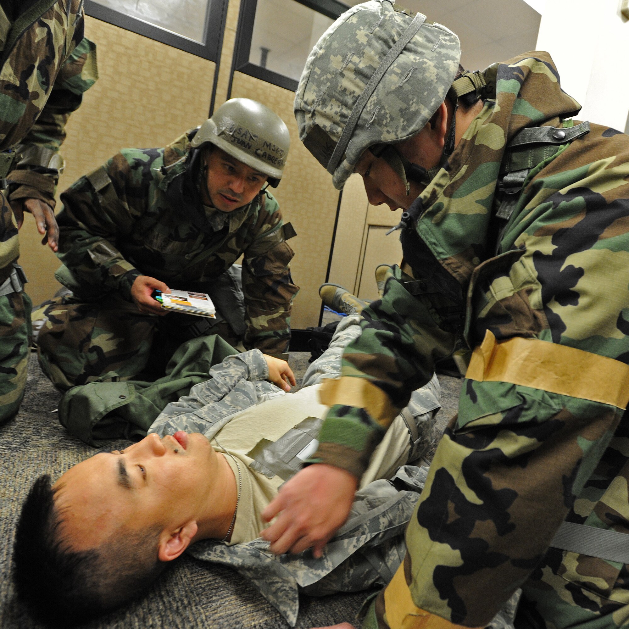 Master Sgt. Juan Cabrera, 15th Comptroller Squadron quality assurance manager, left, and Tech. Sgt. Ryan Yung from 154th Comptroller Flight travel pay technician, right, demonstrate self-aid buddy care procedures on downed Airman at the military pay and finance building, during an Operational Readiness Inspection at Joint Base Pearl Harbor-Hickam, Hawaii, Nov. 7. 2013. Both the 15th Wing and 154th Hawaii Air National Guard Airmen participated in the readiness exercise that tested survival skills in a Total Force Integration environment during stressful situations. (U.S. Air Force photo/Tech. Sgt. Jerome S. Tayborn)
