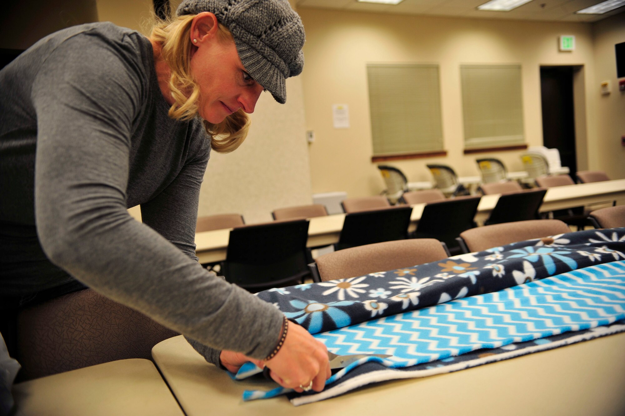 A volunteer cuts patterned fleece Nov. 7, 2013, at the chapel on Buckley Air Force Base, Colo. The Women’s Empowerment Group, Buckley Spouses and Buckley Women’s Ministry, along with women from all over the base, joined together to create blankets to donate to the Comitis Crisis Center in Aurora, Colo. (U.S. Air Force Airman 1st Class Samantha Saulsbury/Released)