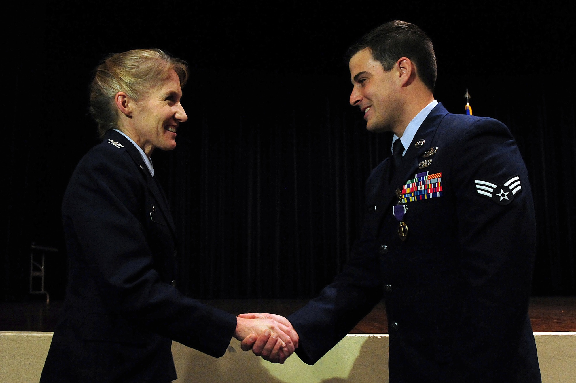 U.S. Air Force Col. Jeannie Leavitt, 4th Fighter Wing commander, presents Senior Airman Justin Beasley, 4th Civil Engineer Squadron explosive ordnance disposal technician, with a coin after a Purple Heart ceremony at Seymour Johnson Air Force Base, N.C., Nov. 8, 2013.  Leavitt was the presiding officer for the ceremony and presented Beasley with his Purple Heart medal, which is awarded to Service members who are wounded in action.  (U.S. Air Force photo by Airman 1st Class Brittain Crolley)