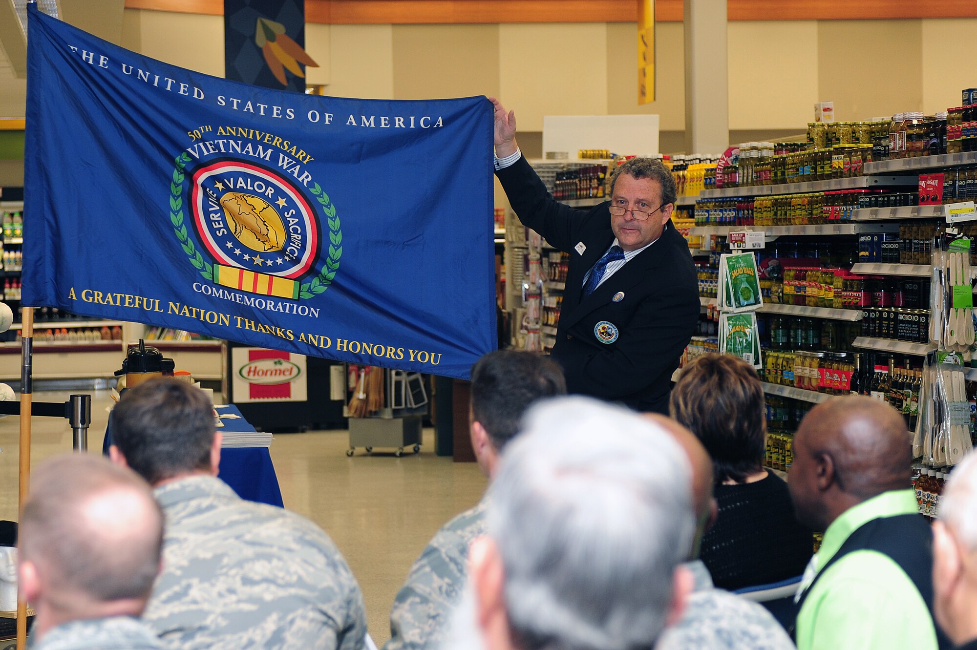 Willard Whitworth, Seymour Johnson Air Force Base Commissary store director, showcases the 50th Anniversary Vietnam War commemoration flag at Seymour Johnson Air Force Base, N.C., Nov. 7, 2013. U.S. Air Force Staff. Sgt. Rachel Bell, 4th Aircraft Maintenance Squadron crew chief, along with Col. Lamar Pettus, 4th Fighter Wing vice commander, and Whitworth unveiled the flag together.  (U.S. Air Force photo by Airman 1st Class John Nieves Camacho)