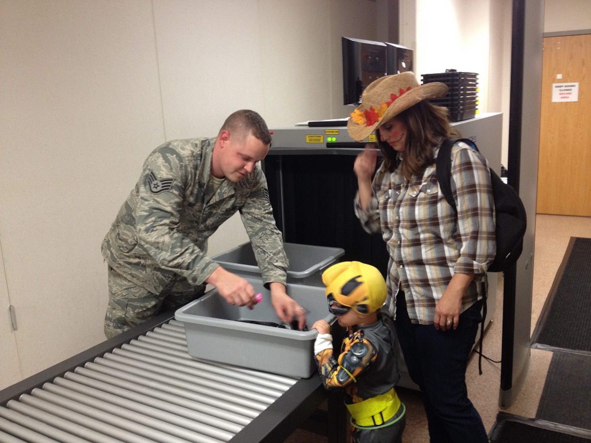 Staff Sgt. Michael Day, 305th Aerial Port Squadron passenger terminal representative, uses the terminal's luggage x-ray machine to inspect children's Halloween candy Oct. 31, 2013, at Joint Base McGuire-Dix-Lakehurst, N.J. Heather Jablonski, wife of Master Sgt. Chris Jablonski, 621st Contingency Operations Support Group first sergeant, watches as Day helps their son Christopher sort through the x-rayed candy. Day hails from Harrah, Okla. and the Jablonski family hails from Fort Walton Beach, Fla. (U.S. Air Force photo by 2nd Lt. Carrie Volpe/Released)
