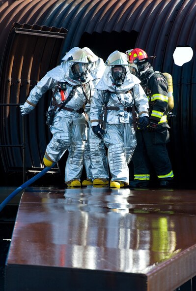 Col. Gretchen Wiltse, 512th Mission Support Group commander, front, walks down the wing of an aircraft fire trainer Nov. 4, 2013, at the fire training area on Dover Air Force Base, Del. Wiltse took part in a joint training exercise for 436th and 512th Civil Engineer Squadron Fire Departments. (U.S. Air Force photo/Roland Balik)