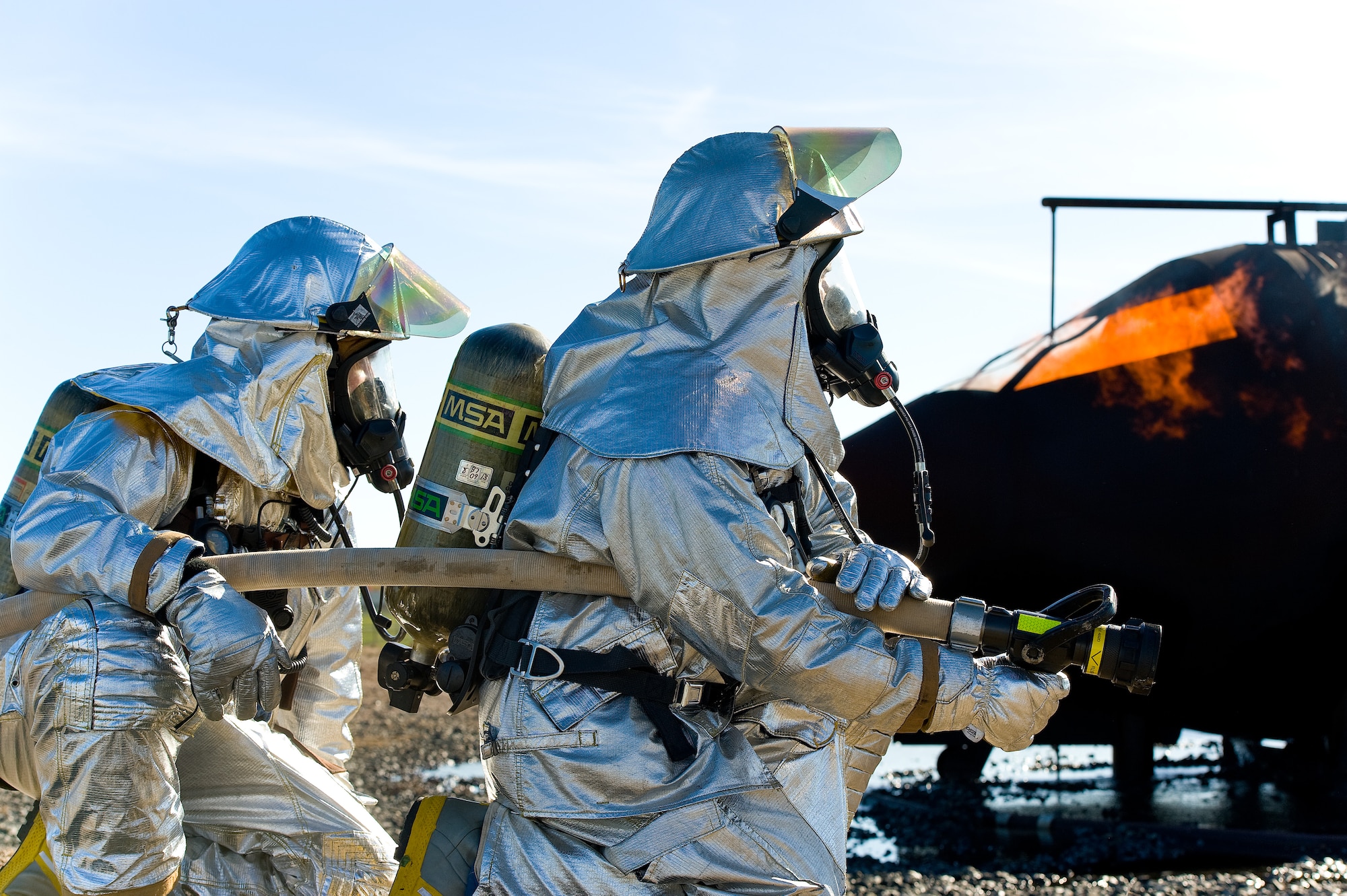 Staff Sgt. David Smith, left, and Senior Airman Jonathon Leopold, right, firefighters from the 436th and 512th Civil Engineer Squadrons, respectively, positioned themselves as a back-up team Nov. 4, 2013, at Dover Air Force Base, Del. They served as a back-up for a two-person fire attack team engaging a simulated aircraft fire. (U.S. Air Force photo/Roland Balik)
