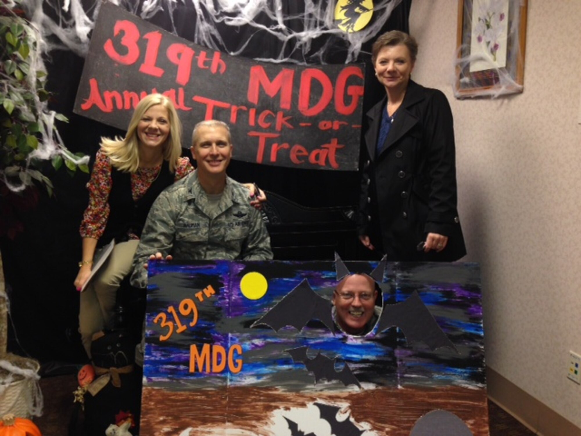 Bonnie Bauman (left) and Col. Paul Bauman, 319th Air Base Wing commander, pose with Rebecca Ann Duncan (right) and 319th ABW Command Chief Master Sgt. David Duncan (sitting in sign) during the 319th Medical Group Trick-or-Treat event Oct. 31, 2013, on Grand Forks Air Force Base, N.D. The 319th Medical Group hosts trick-or-treating every year as a way for children and families to enjoy the holiday. (U.S. Air Force photo courtesy of Col. Terri Bailey)