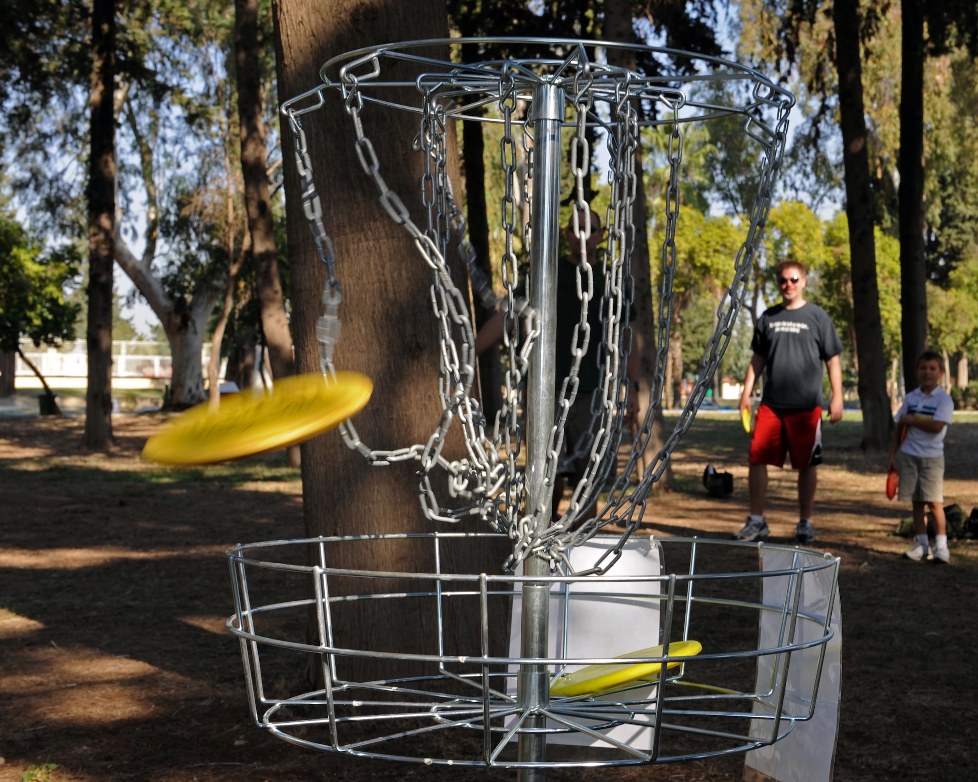 A flying disc punches through the chains of a goal basket during a disc golf clinic event Nov. 2, 2013, at Incirlik Air Base, Turkey. Incirlik AB hosts Turkey’s only PDGA registered course. (U.S. Air Force photo by Senior Airman Chase Hedrick/Released)