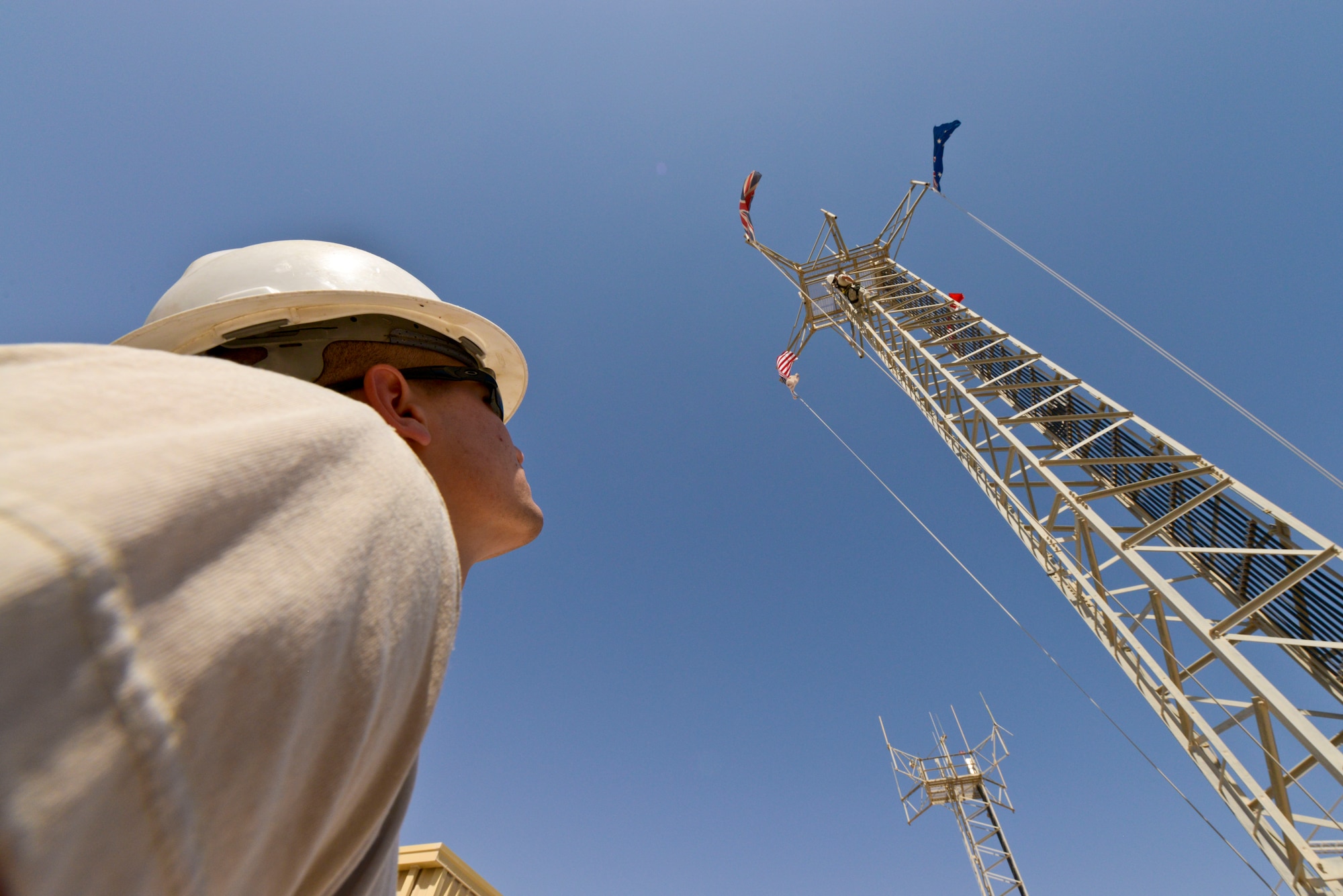 Airman 1st Class Matthew Gambal spots Senior Airman Wong Ly during an antenna tower climb at the 379th Air Expeditionary Wing in Southwest Asia, Oct. 30, 2013. Cable maintainers always operate in pairs for safety precautions.  Cable and antenna maintainers Gambal and Ly are with the 379th Expeditionary Communications Squadron. Gambal is deployed from Barksdale Air Force Base, La., and hails from Caledonia, Miss. and Ly is deployed from Kadena Air Base Japan and a native of Hilo, Hawaii. (U.S. Air Force photo/Tech. Sgt. Joselito Aribuabo)
