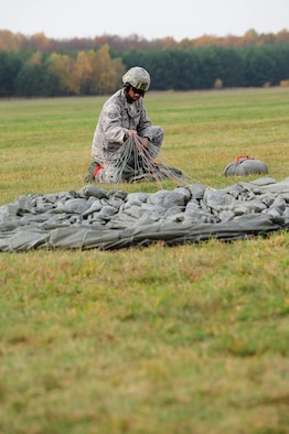 Staff Sgt. Devant Jones, 435th Security Forces Squadron jumpmaster, packs his parachute up after a jump during a theater security cooperation event, Oct. 24, 2013, Powidz Air Transport Base, Poland. Generally, jumpers are used to secure and protect a new landing zone prior to aircraft landing. (U.S. Air Force photo/Senior Airman Hailey Haux)