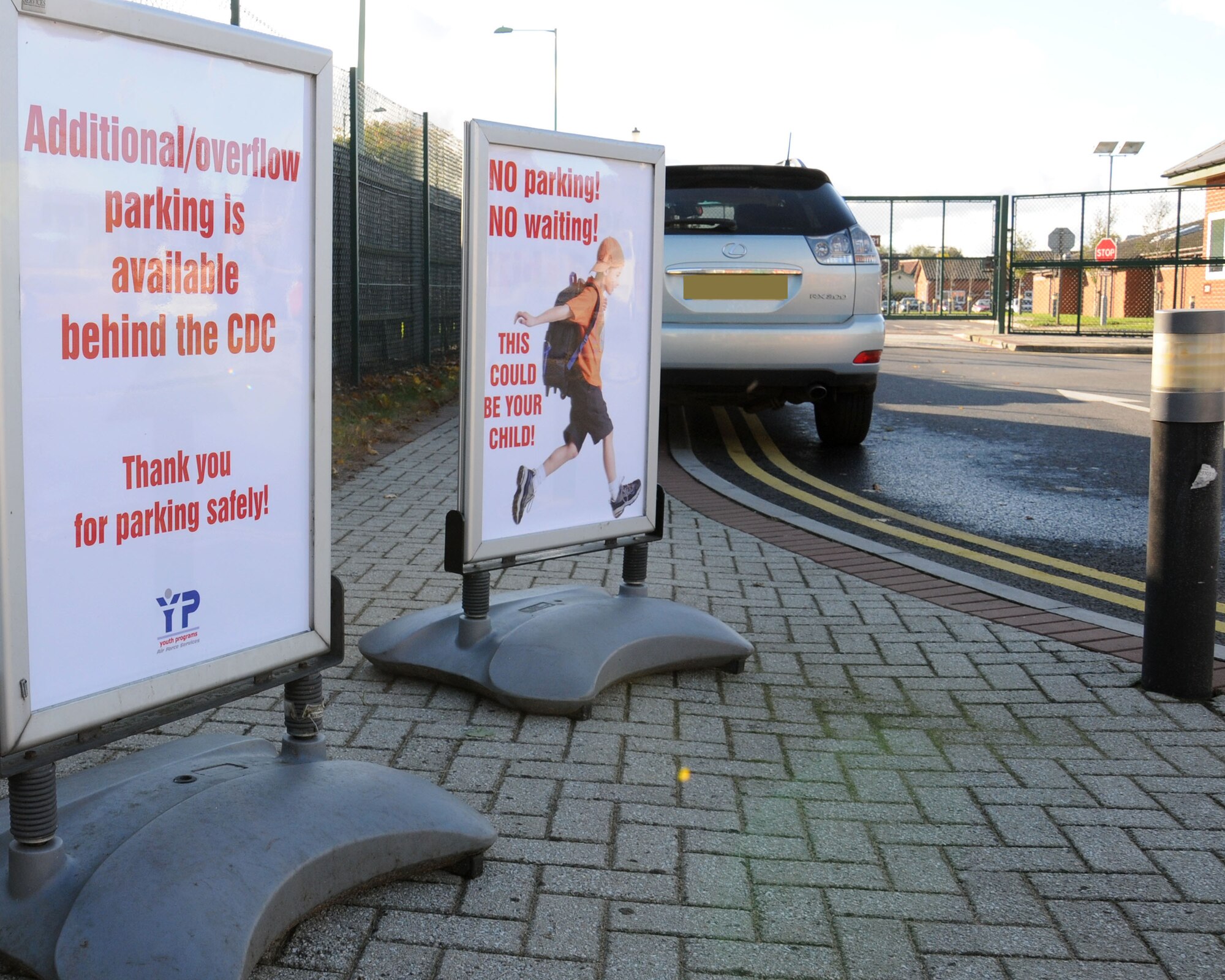 Staff members at the RAF Mildenhall Youth Center place signs to warn parents against parking illegally on double yellow lines Oct. 23, 2013, on RAF Mildenhall, England. Customers have been parking illegally and unsafely on the double yellow lines, and the staff wants to highlight the risk this causes. The staff is also concerned that, as the winter sets in, the days get shorter so reduced visibility causes additional problems. Editor’s note: this photo was edited for privacy purposes.  (U.S. Air Force photo by Gina Randall/Released)