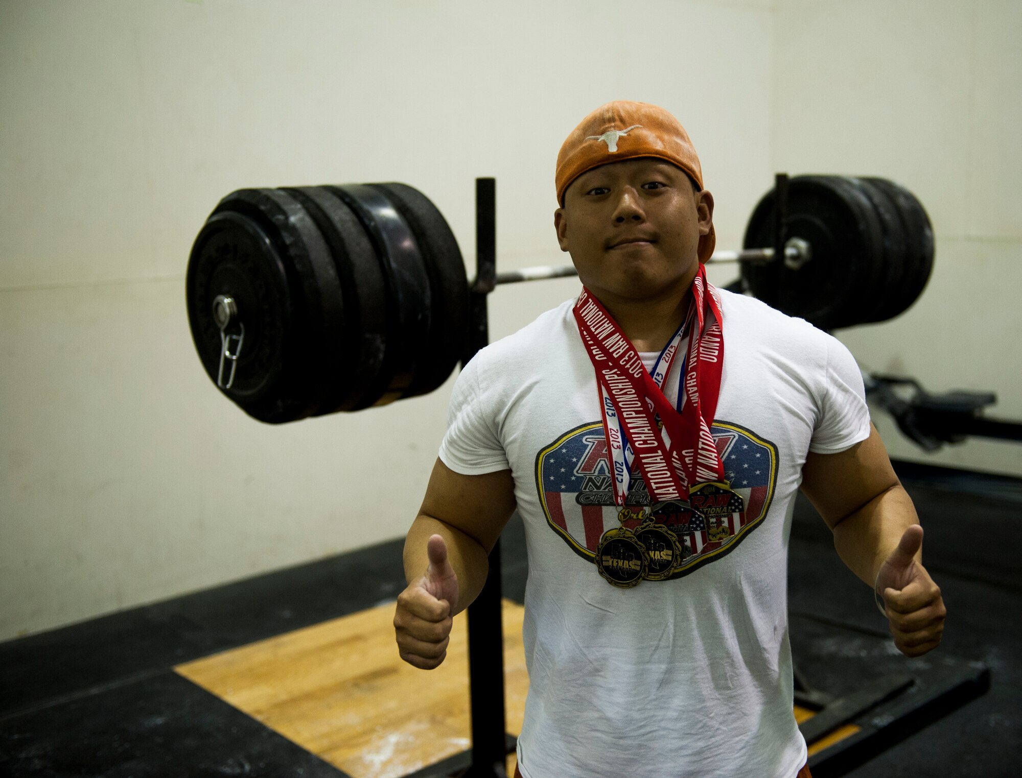 Airman 1st Class Benny Le, 8th Security Forces Squadron response force leader, shows off his recent powerlifting medals at Kunsan Air Base, Republic of Korea fitness center. Le is looking to earn more medals when he represents the Air Force in a military powerlifting competition in March. (U.S. Air Force photo by Senior Airman Clayton Lenhardt/Released)