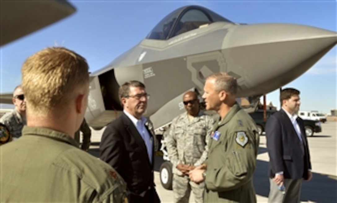 Deputy Secretary of Defense Ashton B. Carter, third from left, receives a briefing on the F-35 Joint Strike Fighter and the F-22 Raptor by Air Force Major Gen. Jeff Lofgren, second from right, and several pilots as he visits Nellis Air Force Base in Las Vegas, Nevada, on Nov. 6, 2013.  