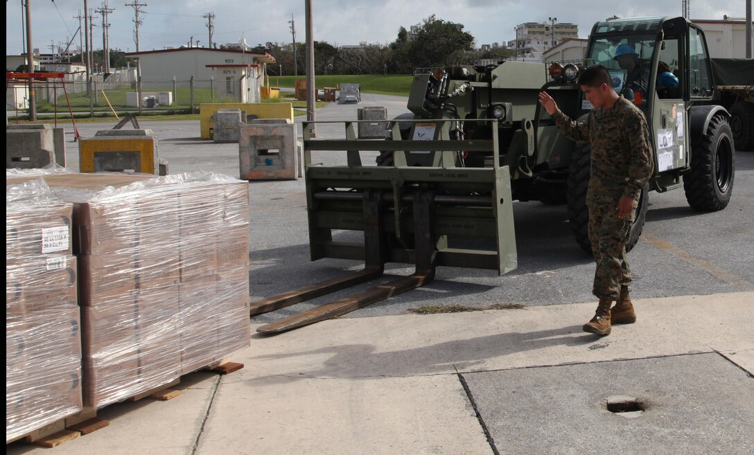 Pfc. Arturo Menchaca uses hand signals to direct Lance Cpl. Bryce E. Sanglay as he drives an extended boom forklift at Marine Corps Air Station Futenma, Okinawa, Japan, Nov. 10 during preparation for a humanitarian assistance and disaster relief mission to the Philippines. Approximately 90 U.S. Marines and Sailors from 3rd Marine Expeditionary Brigade departed on two KC-130J Hercules aircraft. At the request of the Government of the Philippines, Secretary of Defense Chuck Hagel has directed U.S. Pacific Command to support U.S. Government humanitarian assistance and disaster relief operations in the Philippines in the wake of Typhoon Haiyan. Sanglay is a logistics and embarkation specialist with Combat Logistics Battalion 4, Combat Logistics Regiment 3, 3rd Marine Logistics Group, III Marine Expeditionary Force and Menchaca is an engineer equipment operator with III MEF Headquarters Group. The aircraft are with Marine Aerial Refueler Transport Squadron 152, Marine Aircraft Group 36, 1st Marine Aircraft Wing, III MEF. MCAS Futenma is a mission ready air station capable of continuous aviation and base operating support for tenant organizations and follow-on U.S., Allied, and United Nations forces during combat or contingency operations in the Western Pacific Theater of operations, to include U.S. Pacific Command, Marine Corps Forces Pacific and Marine Corps Installations Pacific.