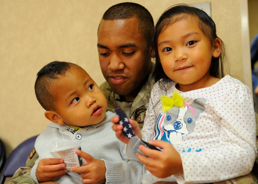 Staff Sgt. Dwight Hicks, 479th Flying Training Group aviation resource manager, sits with his two children, Caley, right, and Dwight Jr., at the Pensacola Bay Center in Pensacola, Fla., Nov. 9, 2013. Hicks returned from his deployment to Bagram Airfield, Afghanistan, right before he surprised his family at the hockey game. (U.S. Air Force photo/Airman 1st Class Jeff Parkinson) 