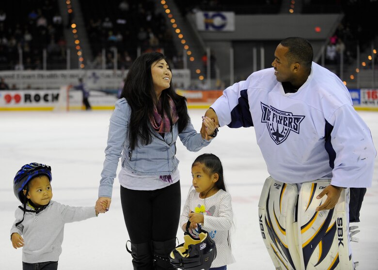 Staff Sgt. Dwight Hicks, 479th Flying Training Group aviation resource manager, walks off the ice with his wife, Eunah, and two children, Caley and Dwight Jr, after a surprise homecoming during a hockey game half time show at the Pensacola Bay Center in Pensacola, Fla., Nov. 9, 2013. Hicks dressed up as a goalie to surprise his family. (U.S. Air Force Photo/Airman 1st Class Jeff Parkinson)