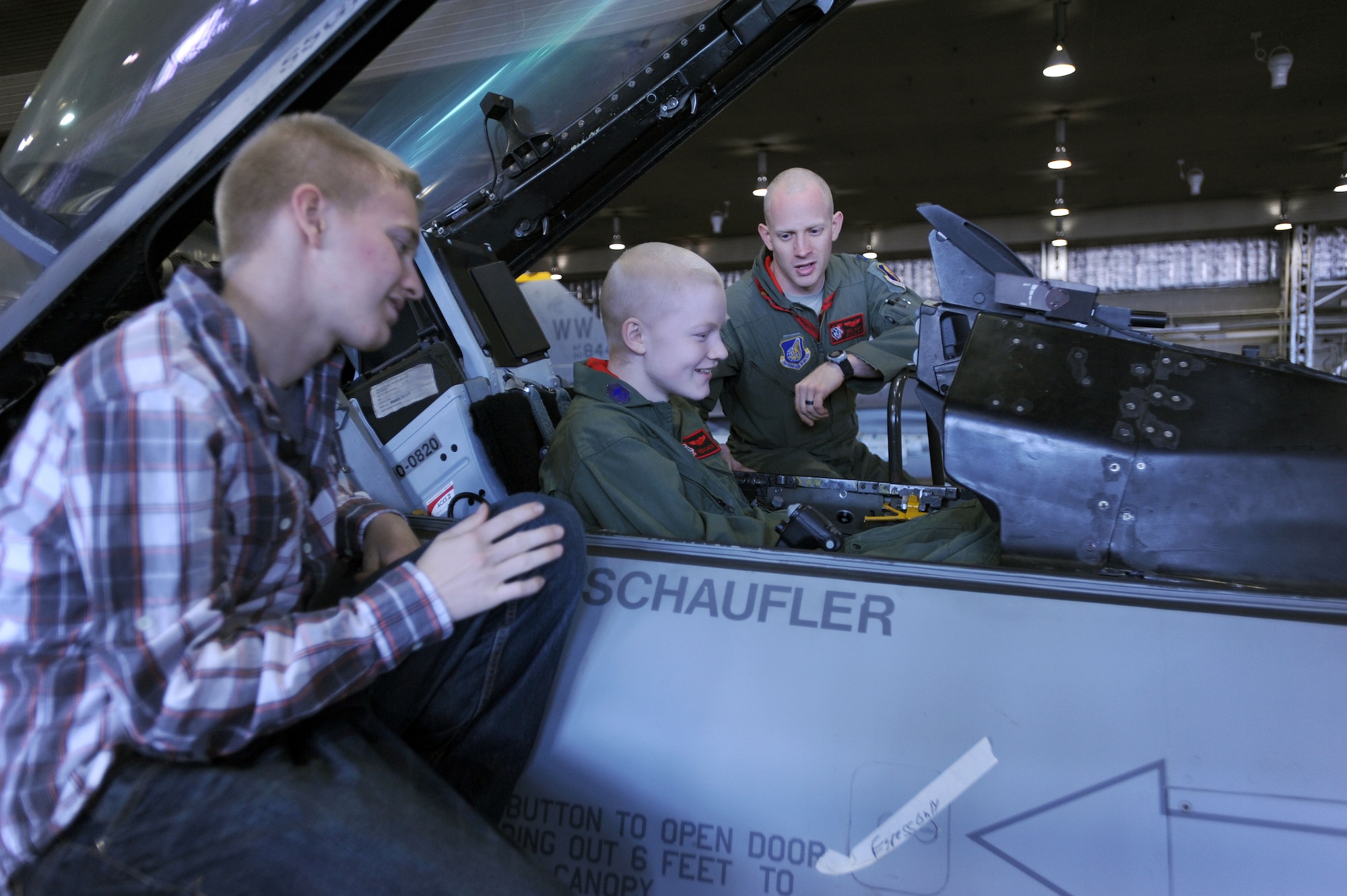Capt. Jonathan Kay, 13th Fighter Squadron fighter pilot (right), explains an F-16CJ cockpit to 17-year-old Jonah Skrove (center), and his brother Airman 1st Class Jared Skrove, 13th Aircraft Maintenance Unit electrical and environmental maintenance specialist (left), at Misawa Air Base, Japan, Nov. 1, 2013. Diagnosed with osteosarcoma last fall, Jonah was given the opportunity through the Make-A-Wish Foundation to do anything or go anywhere he wanted. Jonah wished to visit his brother here, and was treated to a tour of several base agencies during his visit. (U.S. Air Force photo by Staff Sgt. Alyssa C. Wallace/released)