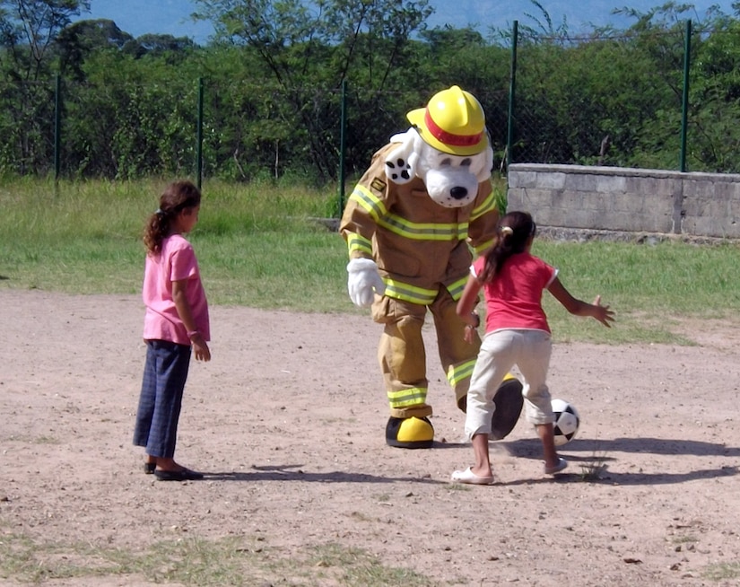 Sparky the Fire Dog plays soccer with children at the Nuestra Seniora de Guadalupe orphanage in Comayagua, Honduras, Nov. 6, 2013.  Twenty-one members of the 612 ABS spent the afternoon at orphanage.  Six children at the orphanage had a birthday during the month of November, and the 612 ABS members brought along birthday gifts to celebrate the occassion.  Members of the 612th spent the afternoon playing and visiting with the children.  (U.S. Air Force photo by Tech. Sgt. Stacy Rogers)