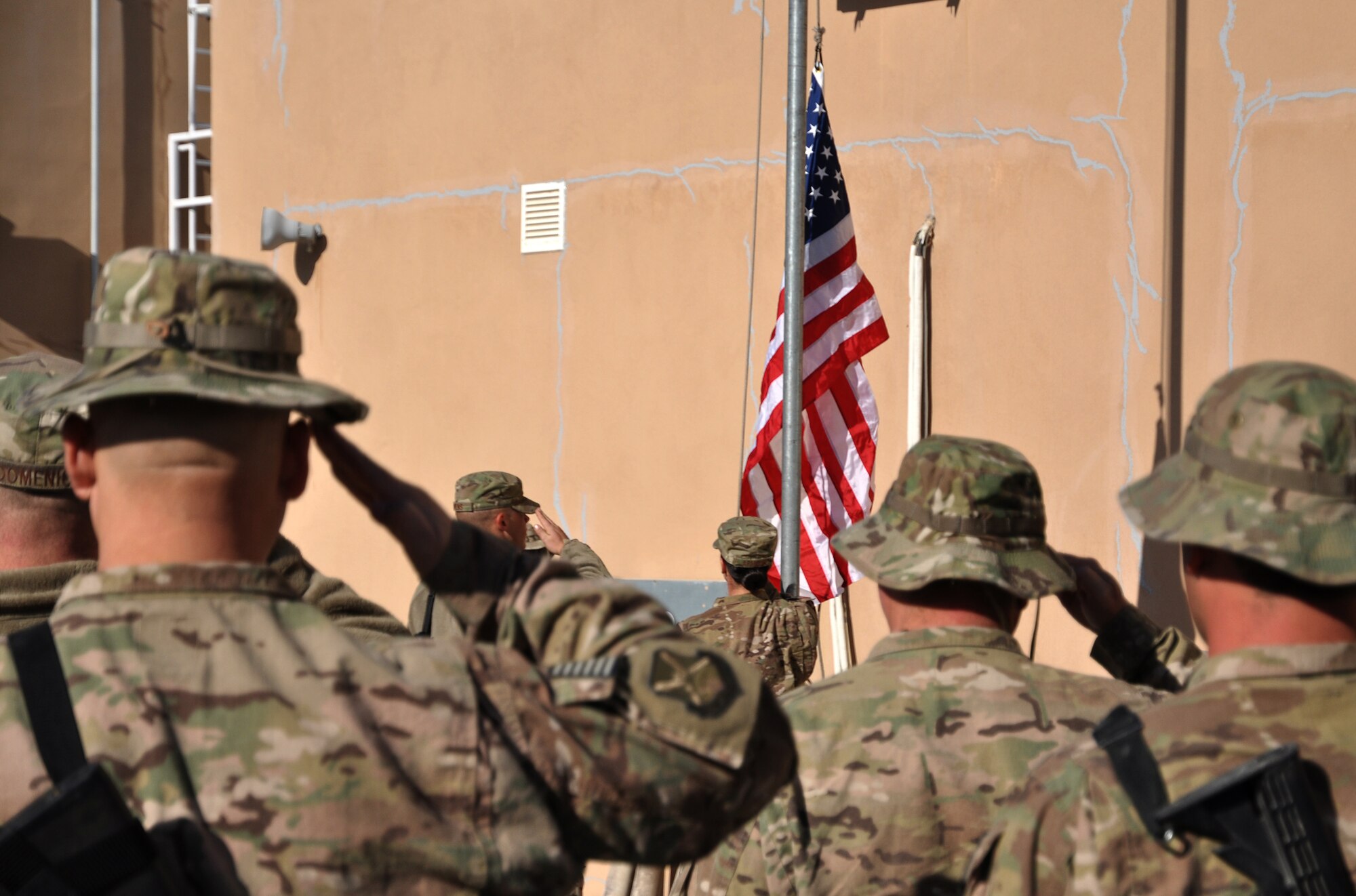Men and women of the 451st Air Expeditionary Wing, Kandahar Airfield, Afghanistan, salute while the American flag is raised at Camp Losano Nov. 11, 2013 – Veterans Day. A team of personnel from the 451st AEW flew 16 American flags over the camp for individuals who wanted to commemorate the day with a flag. Each flag flown will be accompanied with a certificate. (U.S. Air Force photo by Capt. Jason Smith)