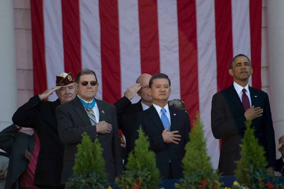 President Barack Obama and Veterans Affairs Secretary Eric Shinseki stand for the presentation of the colors during the Veterans Day ceremony at Arlington National Cemetery in Arlington, Va., Nov. 11, 2013.