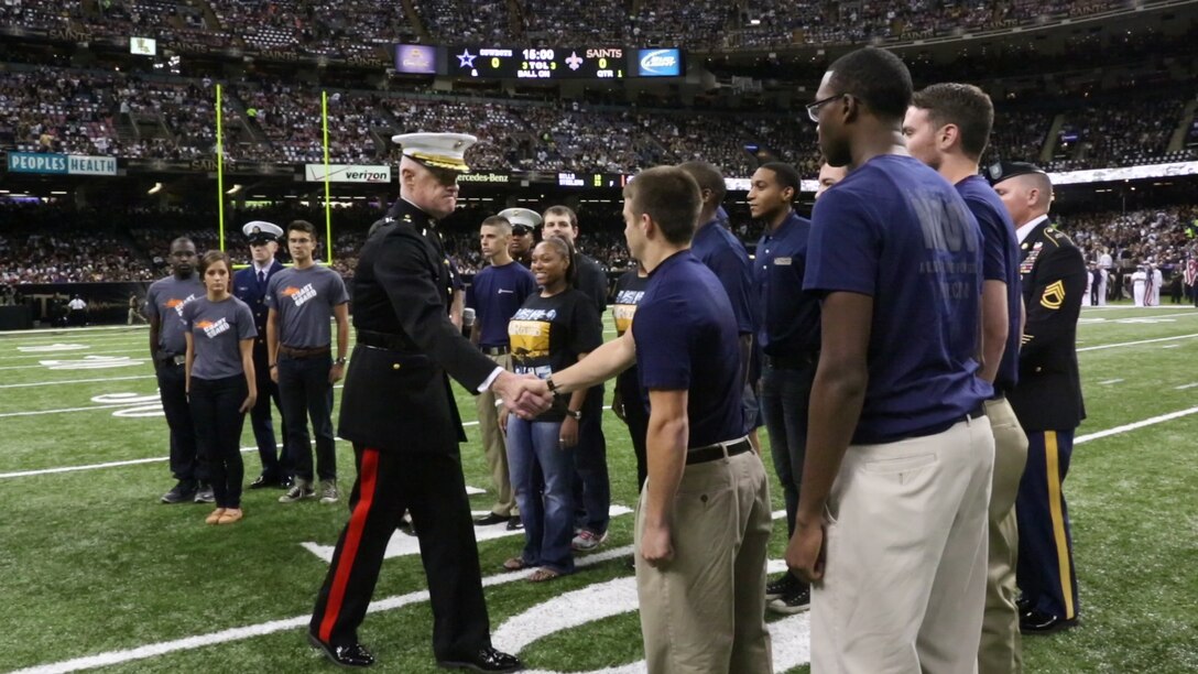 Lt. Gen. Richard P. Mills, commander of Marine Forces Reserve and Marine Forces North, congratulates enlistees after leading them in the traditional oath of enlistment prior to joining the military during the National Football League's New Orleans Saints  vs. the Dallas Cowboys game, Nov. 10, 2013. 