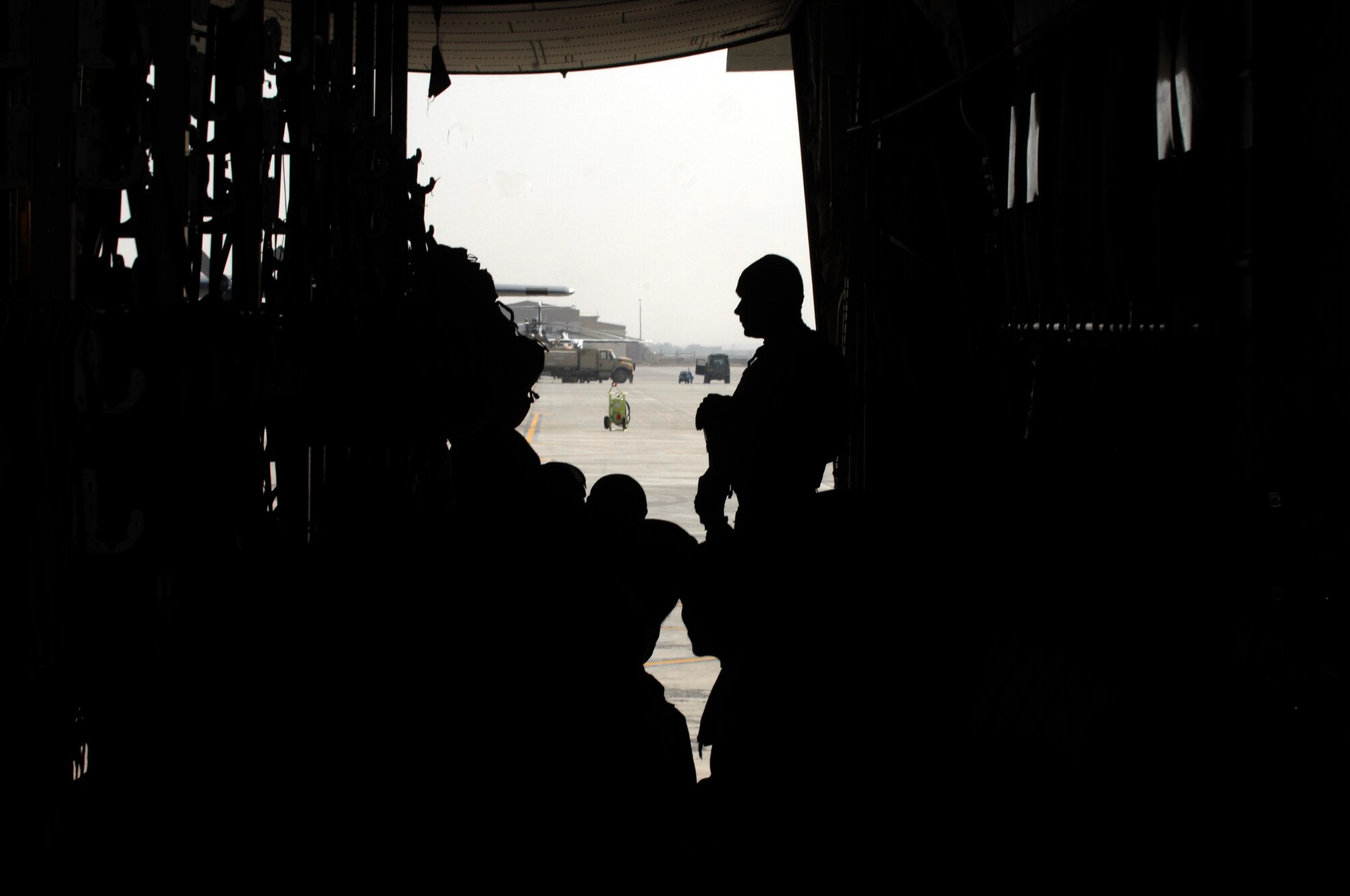 Staff Sgt. Steve McCoy, 451st Expeditionary Security Forces Squadron Fly Away Security Team (silhouetted), stands at the back of a C-130J Hercules waiting to allow passengers to leave the aircraft, Nov. 2, 2013. FAST members provide security for the aircraft, crews and passengers as they fly to different locations in Southwest Asia. (U.S. Air Force photo by Senior Airman Jack Sanders)