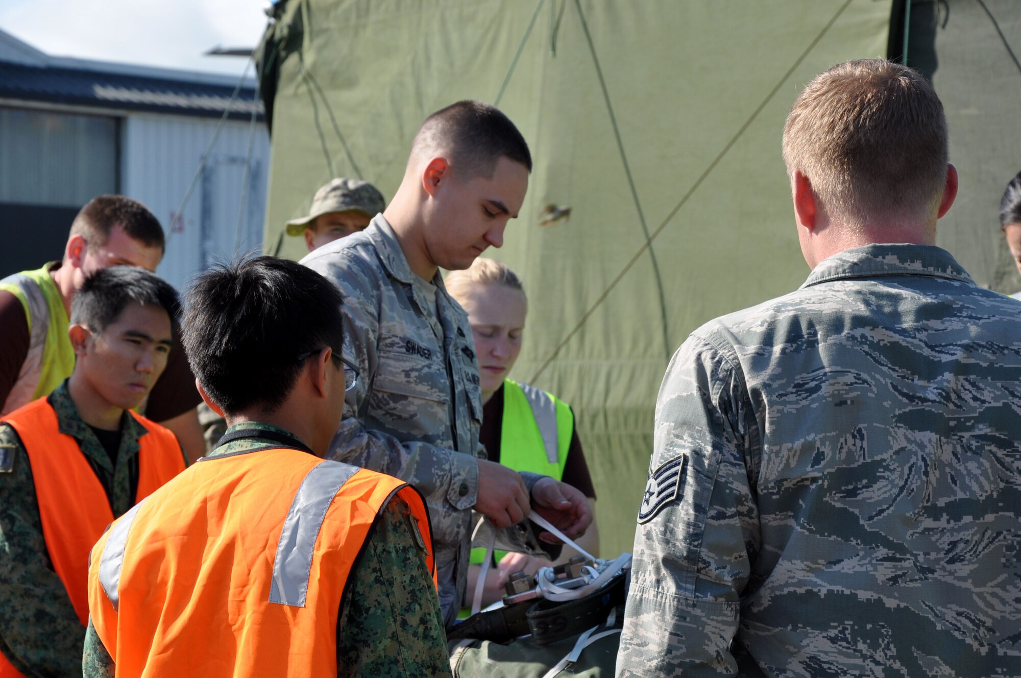 U.S. Air Force Staff Sgt. Kyle Swader, 517th Expeditionary Airlift Squadron combat mobility specialist, weaves a length of one-quarter inch cotton webbing through a drogue parachute as military parachute riggers from three nations joined together for a subject-matter exchange at Royal New Zealand Air Force Base Ohakea, New Zealand, Nov. 11 during the second annual Exercise Kiwi Flag. U.S. Air Force trainers, deployed to the 517th Expeditionary Airlift Squadron, taught attendees how to rig a “15-foot extraction chute to the 160-foot extraction line” for cargo air drops from the C-17 Globemaster III. The small drogue chute, attached to a 60-foot line, sits in the back of the aircraft where it is pre-staged to catch the air current from the open ramp when activated mid-flight. When the drogue chute catches the current, the drogue rapidly pulls the extraction package, which in turn, pulls the cargo through the opening in the rear of the plane. A combat mobility team, deployed from the 773rd Logistics Readiness Squadron at Joint Base Elmendorf-Richardson, Alaska, trained more than 20 personnel from the New Zealand Army, the RNZAF and the Republic of Singapore Air Force. The Pacific-partners will have numerous opportunities to practice the newly-attained skill during the exercise which runs through Nov. 29. Kiwi Flag personnel are supporting Exercise Southern Katipo -- held on New Zealand’s South Island -- by managing air operations and providing cargo and passenger airlift including tactical air drops to SK participants. Swader calls Topeka, Kansas, home. (U.S. Air Force Photo by Senior Master Sgt. Denise Johnson/Released)
