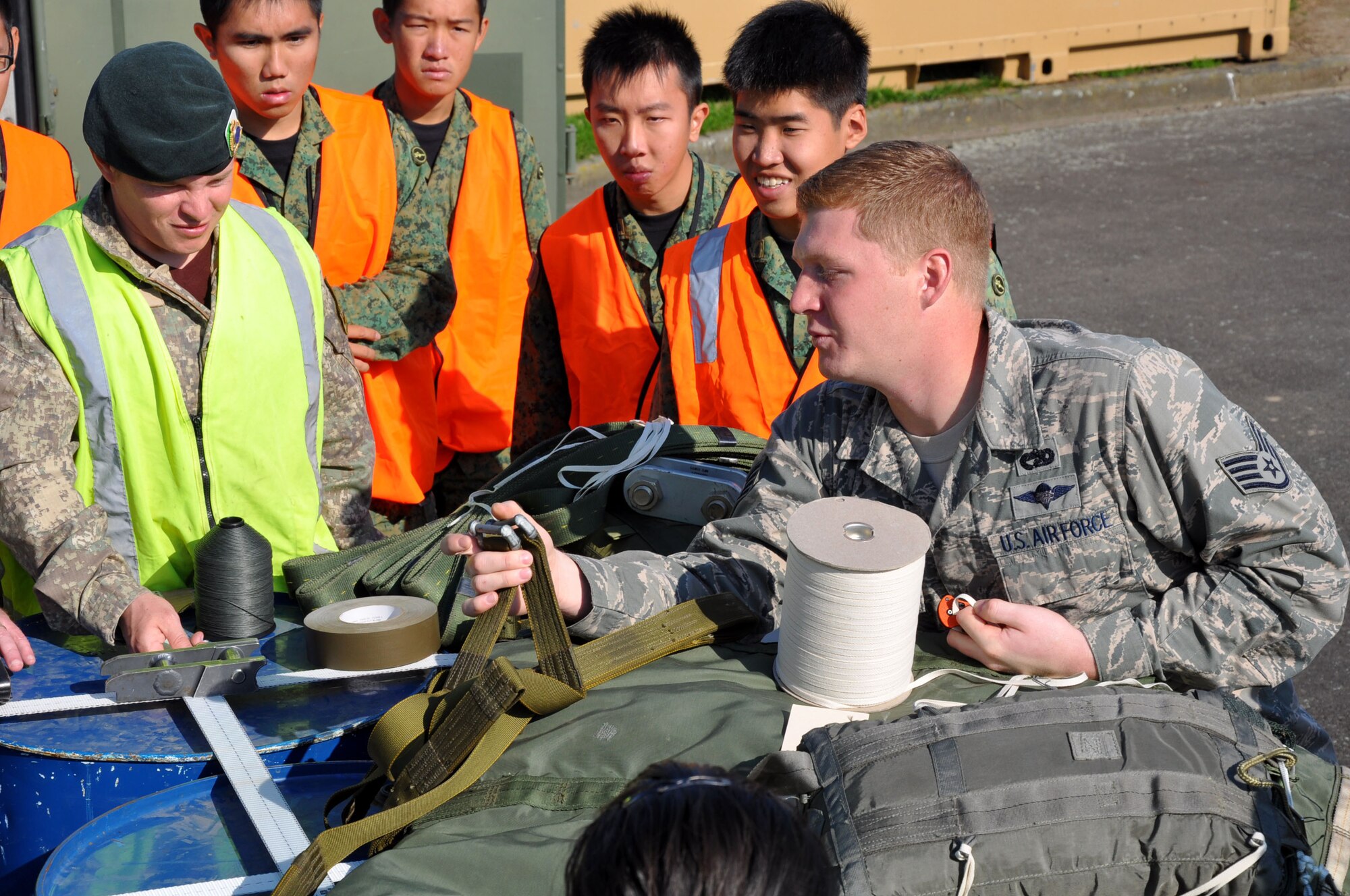 U.S. Air Force Staff Sgt. Bryan Rogers, 517th Expeditionary Airlift Squadron combat mobility specialist, demonstrates how to rig a drogue parachute for the C-17 Globemaster III as parachute riggers from three nations joined together for a subject-matter exchange at Royal New Zealand Air Force Base Ohakea, New Zealand, Nov. 11 during the second annual Exercise Kiwi Flag. U.S. Air Force trainers deployed to the 517th Expeditionary Airlift Squadron taught attendees how to rig a “15-foot extraction chute to the 160-foot extraction line” for cargo air drops from the C-17 Globemaster III. The small drogue chute, attached to a 60-foot line, sits in the back of the aircraft where it is pre-staged to catch the air current from the open ramp when activated mid-flight. When the drogue chute catches the current, the drogue rapidly pulls the extraction package, which in turn, pulls the cargo through the opening in the rear of the plane. The combat mobility team, deployed from the 773rd Logistics Readiness Squadron at Joint Base Elmendorf-Richardson, Alaska, trained more than 20 personnel from the New Zealand Army, the RNZAF and the Republic of Singapore Air Force. The Pacific-partners will have numerous opportunities to practice the newly-attained skill during the exercise which runs through Nov. 29. Kiwi Flag personnel are supporting Exercise Southern Katipo -- held on New Zealand’s South Island -- by managing air operations and providing cargo and passenger airlift including tactical air drops to SK participants. Rogers hails from Virginia Beach, Va. (U.S. Air Force Photo by Senior Master Sgt. Denise Johnson/Released)