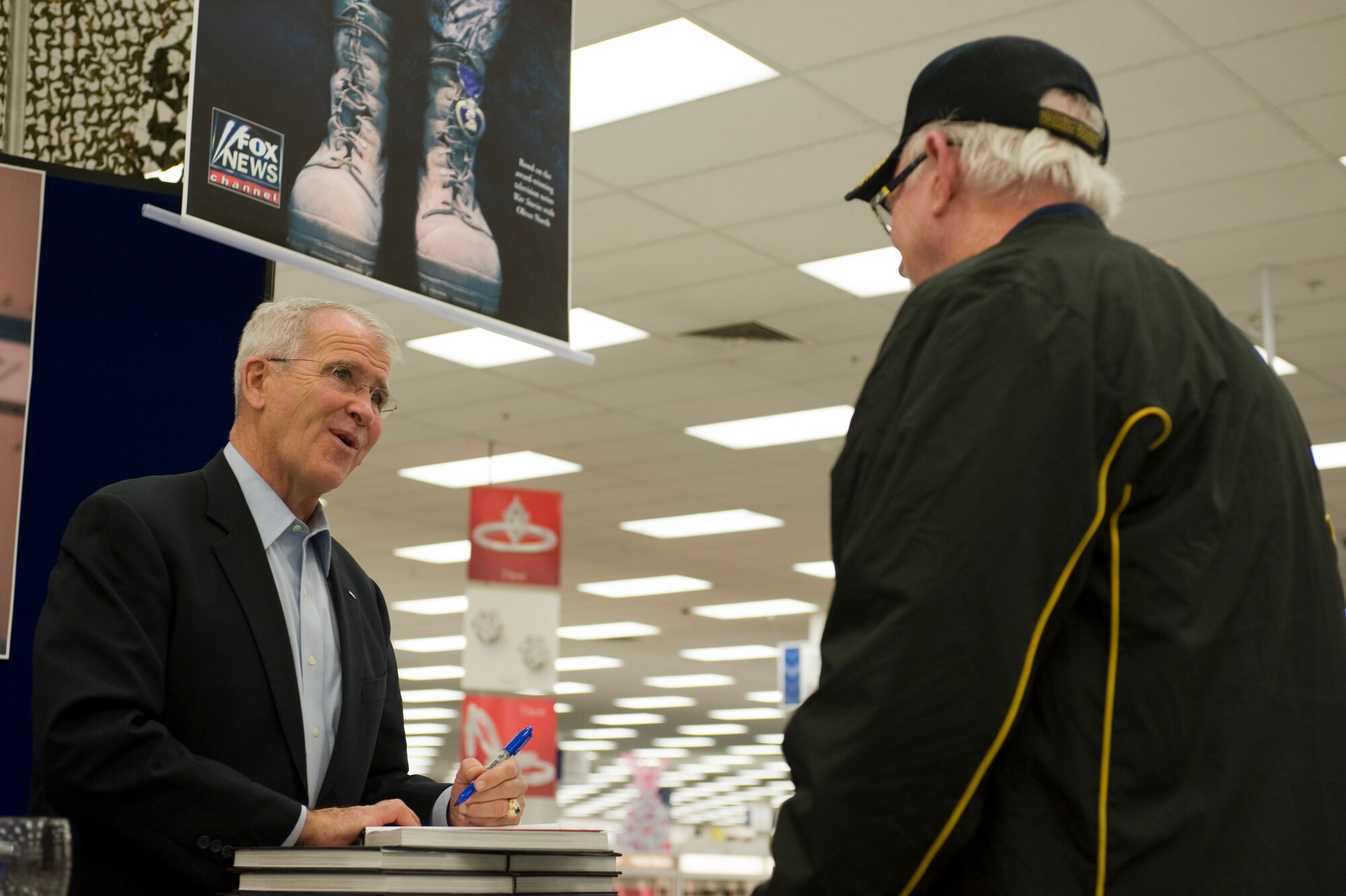 Oliver North, signs an autograph for retired Chief Master Sgt. Grady Griffin, at the Exchange during a book signing Nov. 9, 2013, at Nellis Air Force Base, Nev. North signed autographs for his book “American Heroes, On the Homefront” during his visit to Nellis AFB. North served 22 years in the U.S. Marine Corps and retired at the rank of lieutenant colonel. (U.S. Air Force photo by Airman 1st Class Christopher Tam)