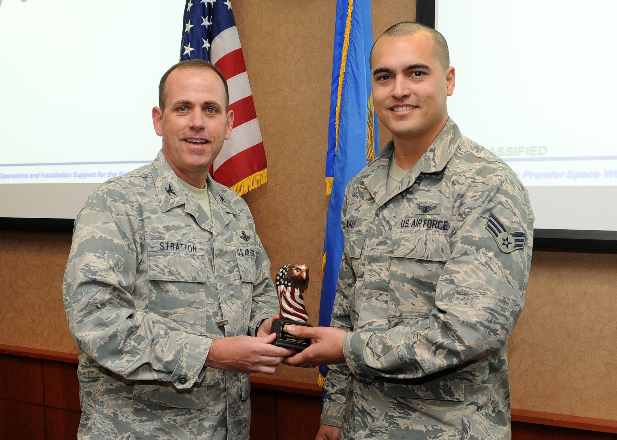 Senior Airman Gary Nagy, 460th Space Wing Inspector General inspection planner, receives the Airman of the Month Award for September from Col. Mitch D. Stratton, 460th SW vice commander, Nov. 12, 2013, at Buckley Air Force Base, Colo. Nagy received the award for his exceptional service in leading 36 satellite sorties in six operational shifts while delivering mission warning capabilities for the president of the United States and nine combatant commands, thus safe guarding 130,000 warfighters. Nagy also trained as an initial Air Force inspection system and commander’s inspection program cadre, and he was selected for a critical wing inspection team position. (U.S. Air Force photo by Senior Airman Marcy Copeland/Released)