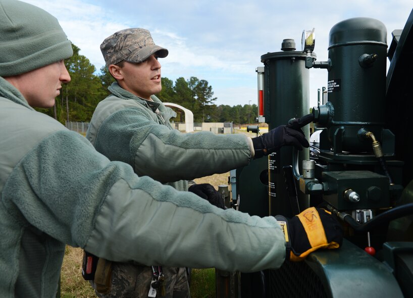 U.S. Air Force Senior Airman Andre Laperle, 20th Civil Engineering Squadron power productions journeyman, shows fire department Airmen how to properly operate the mobile aircraft arresting system, Shaw Air Force Base, S.C., Nov. 6, 2013. Power productions Airmen train the fire department monthly on aircraft arresting systems, instructing on the proper use of the equipment. (U.S. Air Force photo by Senior Airman Tabatha Zarrella/Released)
