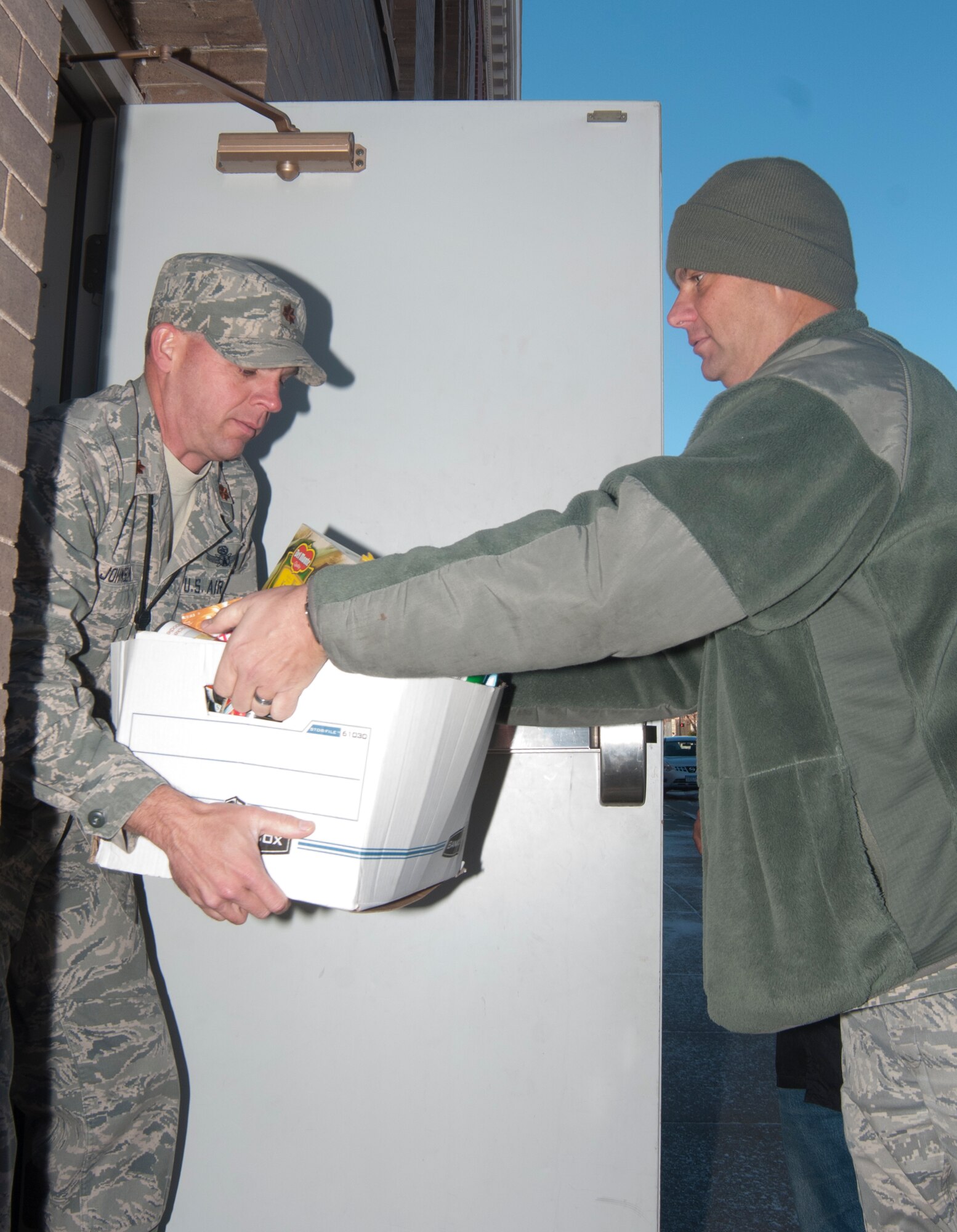 Master Sgt. Brian Hill, 90th Missile Wing Command Post superintendent, hands a box of donated food items to Maj. Darrel Johnson, 90th MW CP chief, while transporting the food to Cheyenne’s Masonic Temple Nov. 5, 2013. The food went to the Cheyenne Appreciates Its Military Foundation, which hosts an annual free military Thanksgiving dinner each year. This year’s dinner will be Nov. 28 from 11 a.m. to 4 p.m. at the Masonic Temple at the crossing of Capital Avenue and West 19th Street. (U.S. Air Force photo by Airman 1st Class Jason Wiese)