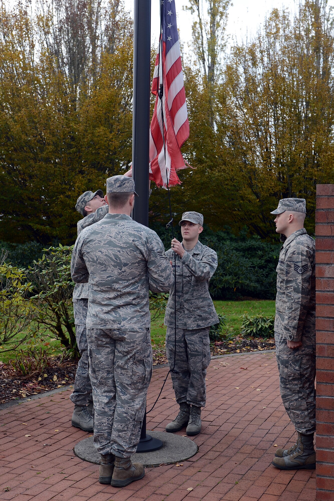 Team McChord Airmen lower a tattered U.S. flag from a flag pole at Memorial Grove Park, Nov. 11, 2013, during a flag exchange ceremony in recognition of Veterans Day at Joint Base Lewis-McChord, Wash. Staff members from the Julius A. Kolb Airman Leadership School here organized and sponsored the event to honor past and present Veterans and their sacrifices on Veterans Day.(U.S. Air Force Photo/Airman 1st Class Jacob Jimenez) 