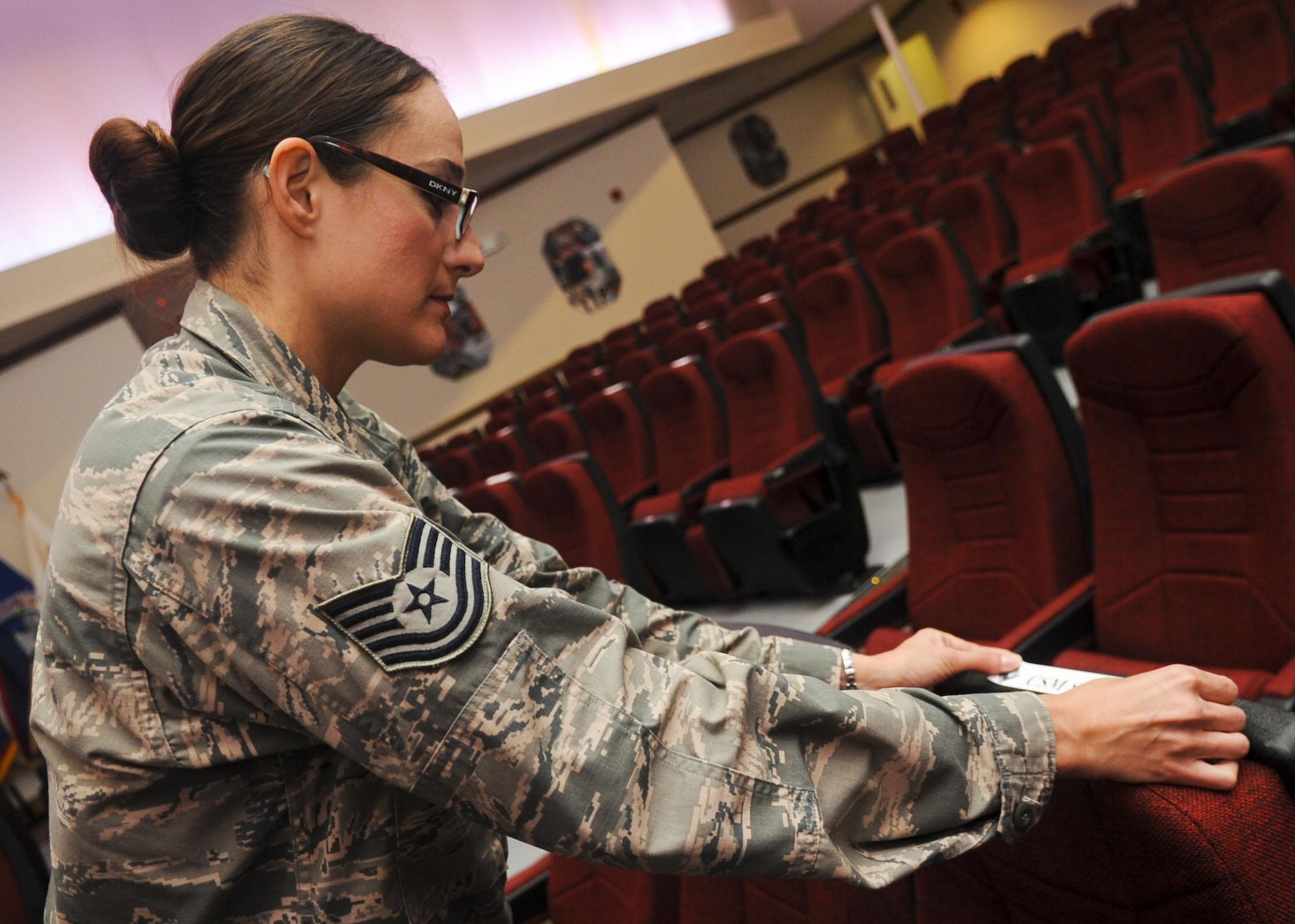 U.S. Air Force Tech. Sgt. Mary Atkinson, 633rd Air Base Wing protocol specialist, places name plates on chairs before a retirement ceremony at Fort Eustis, Va., Sept. 20, 2013. Protocol officials coordinate with units who host an event to ensure ceremony standards are maintained. (U.S. Air Force photo by Airman 1st Class Austin Harvill/Released)