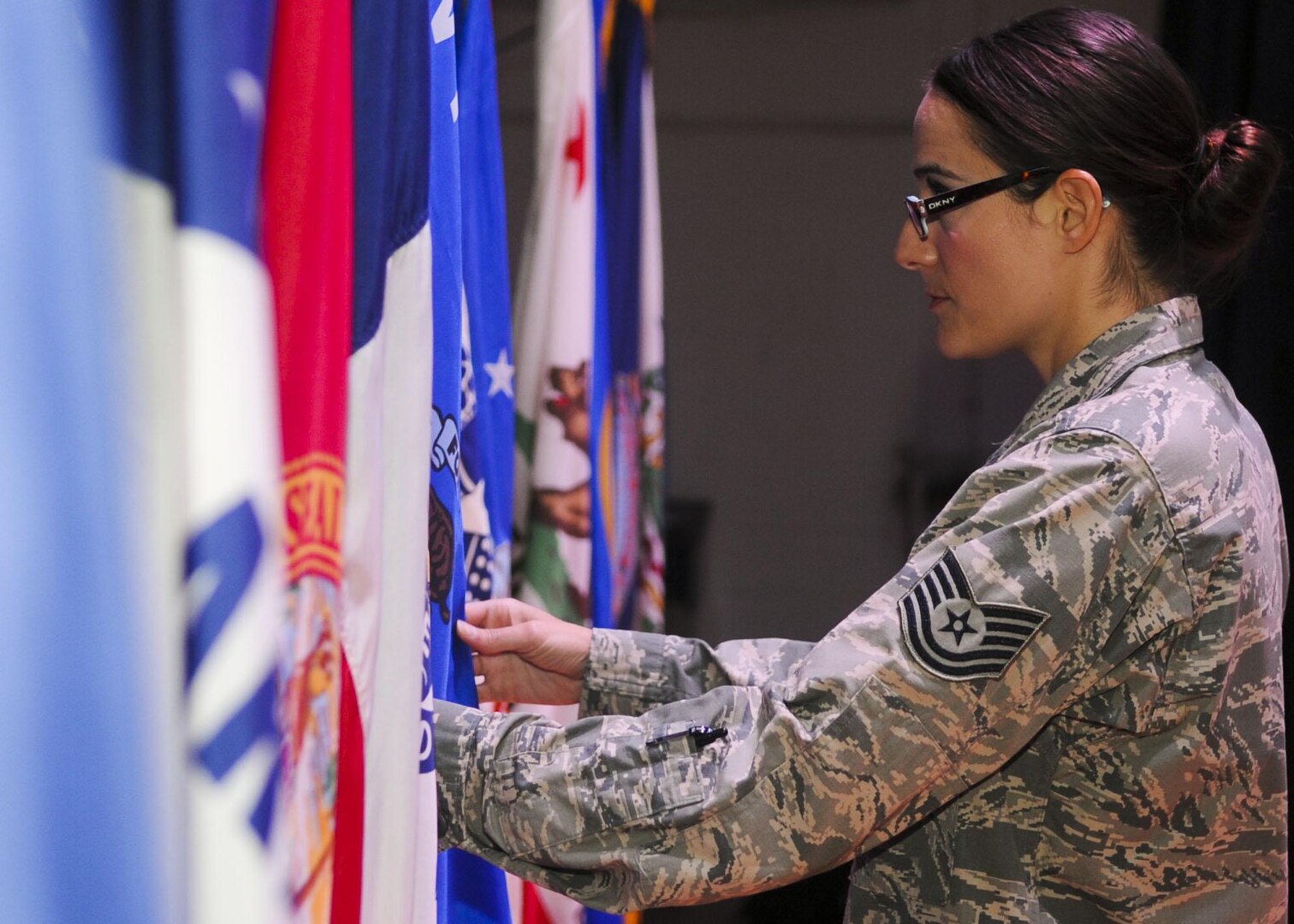 U.S. Air Force Tech. Sgt. Mary Atkinson, 633rd Air Base Wing protocol specialist, positions a unit flag before a retirement ceremony at Fort Eustis, Va., Sept. 20, 2013. Assigning seats, determining program layouts and determining audience size are only a few of the protocol office's duties. (U.S. Air Force photo by Airman 1st Class Austin Harvill/Released)