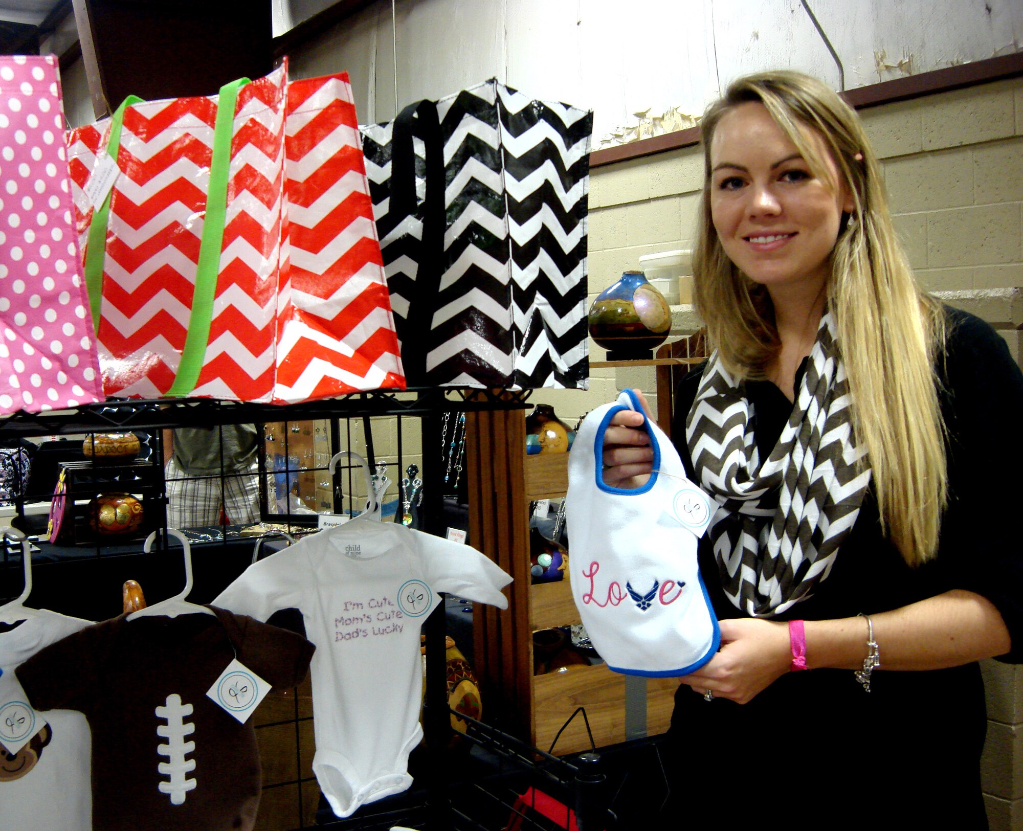 Laura Rice, a military family member and owner of L Embroidery & Design, showcases tote bags, scarves and embroidered baby bibs at the Vance Officers’ Spouses’ Club annual Holiday Marketplace, Nov. 9, at the Chisholm Trail Expo Center in Enid. (U.S. Air Force photo/ Sarina Houston)