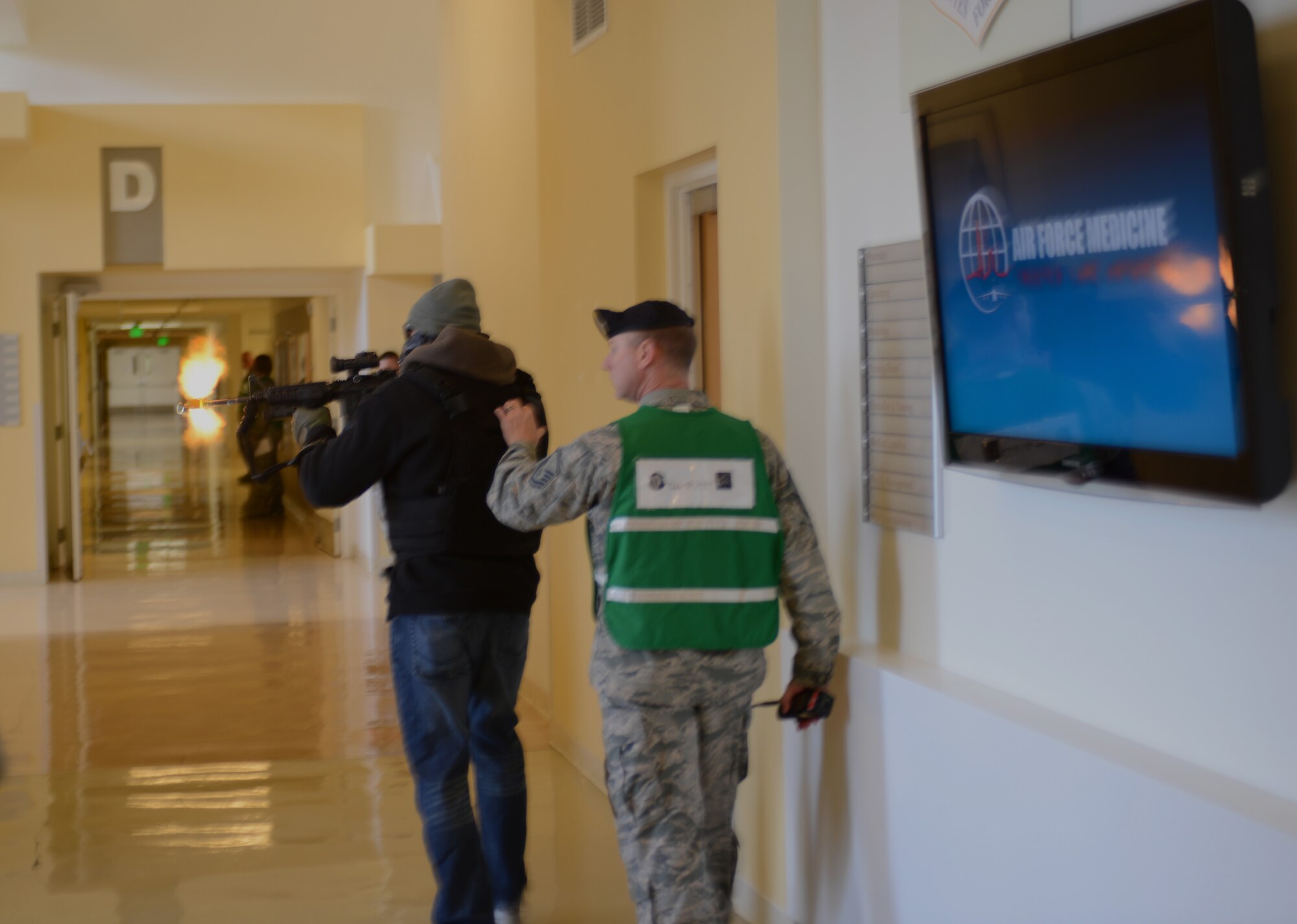 Staff Sgt. Mike Hejmanowski, 366th Security Forces Squadron evaluator, fires blank rounds inside the base hospital while Master Sgt. Francis Woznick, 366th SFS NCO in charge of standards and evaluations monitors alongside him for safety reasons Nov. 6, 2013, during an active-shooter training exercise at Mountain Home Air Force Base, Idaho. Afterward, Woznick explained the steps individuals must take in order to protect themselves during an active shooter rampage. (U.S. Air Force photo by Senior Airman Benjamin Sutton/RELEASED
