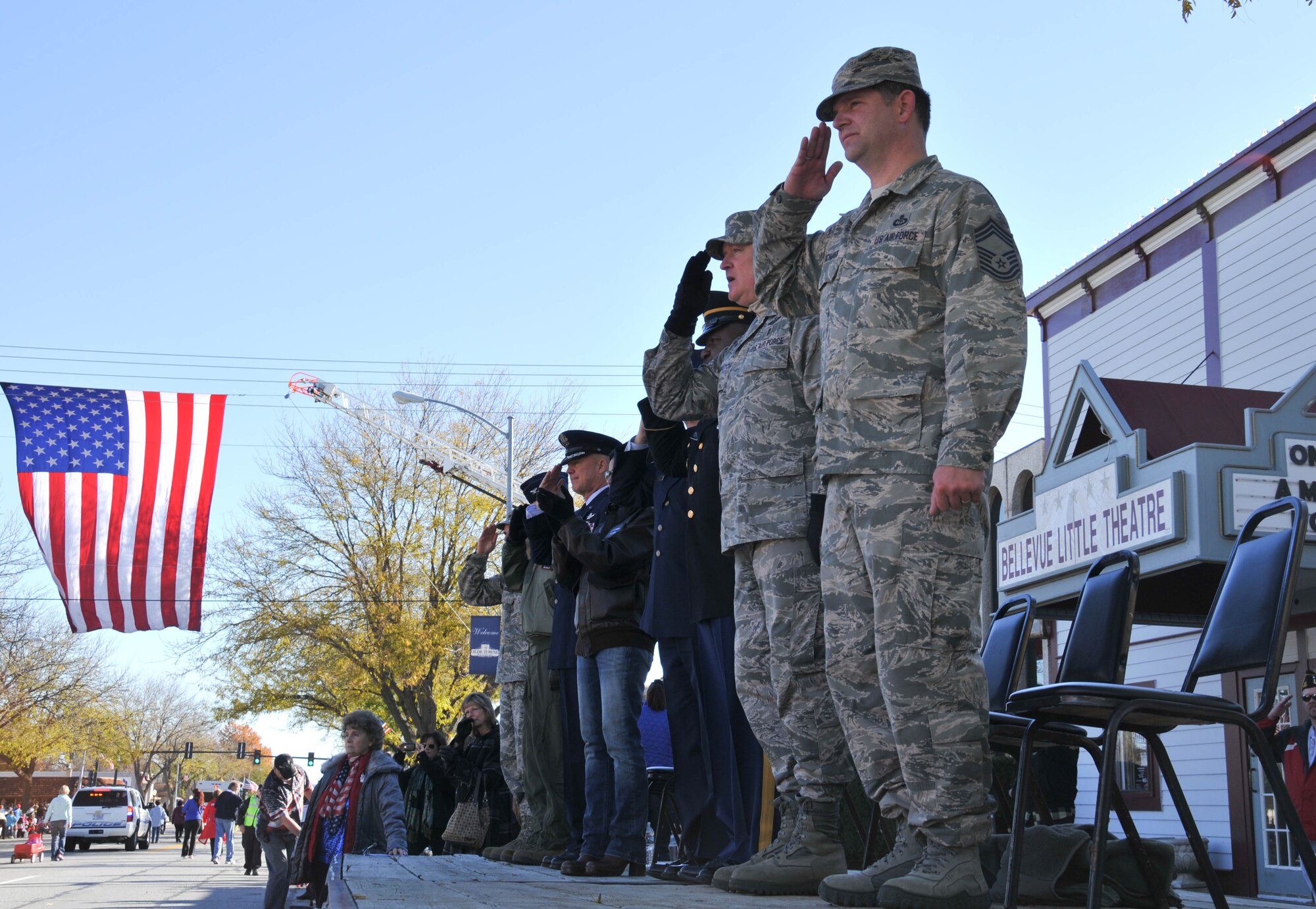 The distinguished guests on the reviewing stand salute participants of the 14th annual Veterans Day Parade in Olde Towne Bellevue, Neb., Nov. 9, as the march by. The 55th Wing, U.S. Strategic Command and Air Force Weather Agency joined with members from the community to honor veterans at this annual parade. (U.S. Air Force photo by 2nd Lt. Carly A. Costello/Released)