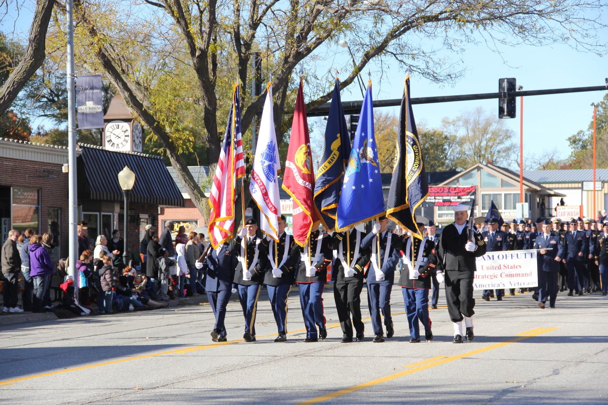 The U.S. Strategic Command Joint Honor Guard, representing the Army, Air Force, Navy and Marine Corps, marches down Mission Avenue during the 14th annual Veterans Day Parade in Olde Towne Bellevue, Neb., Nov. 9. The 55th Wing, U.S. STRATCOM and Air Force Weather Agency joined with the members from the community to honor veterans at this annual parade. (U.S. Air Force photo by 2nd Lt. Carly A. Costello/Released)