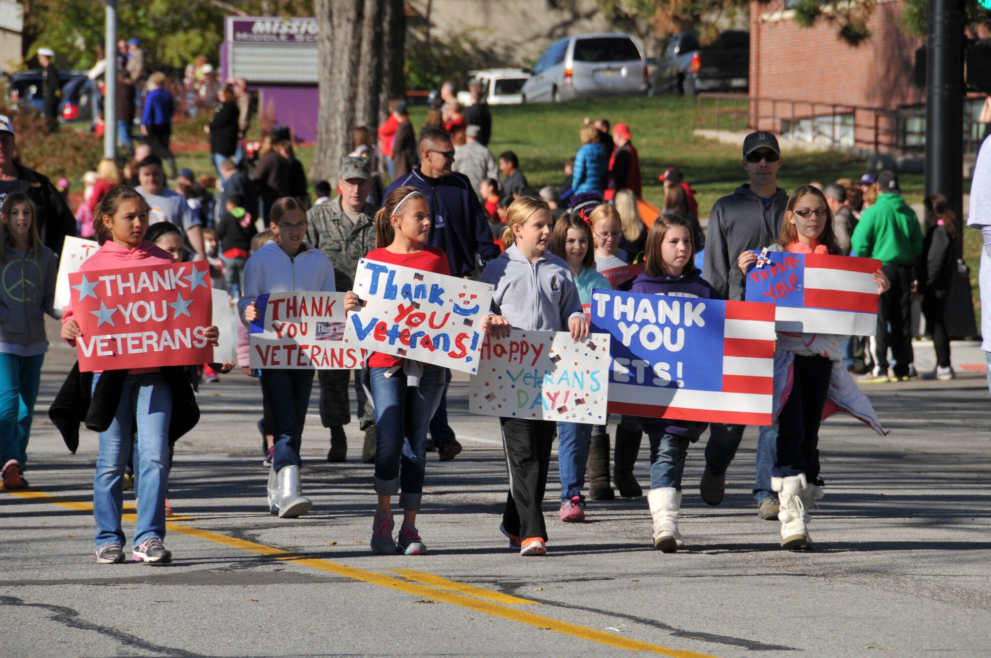 Bellevue Public School students hold handmade signs to honor veterans as they march in the 14th annual Veterans Day Parade in Olde Towne Bellevue, Neb., Nov. 9. The 55th Wing, U.S. Strategic Command and Air Force Weather Agency joined with members from the community to honor veterans at this annual parade. (U.S. Air Force photo by 2nd Lt. Carly A. Costello/Released)