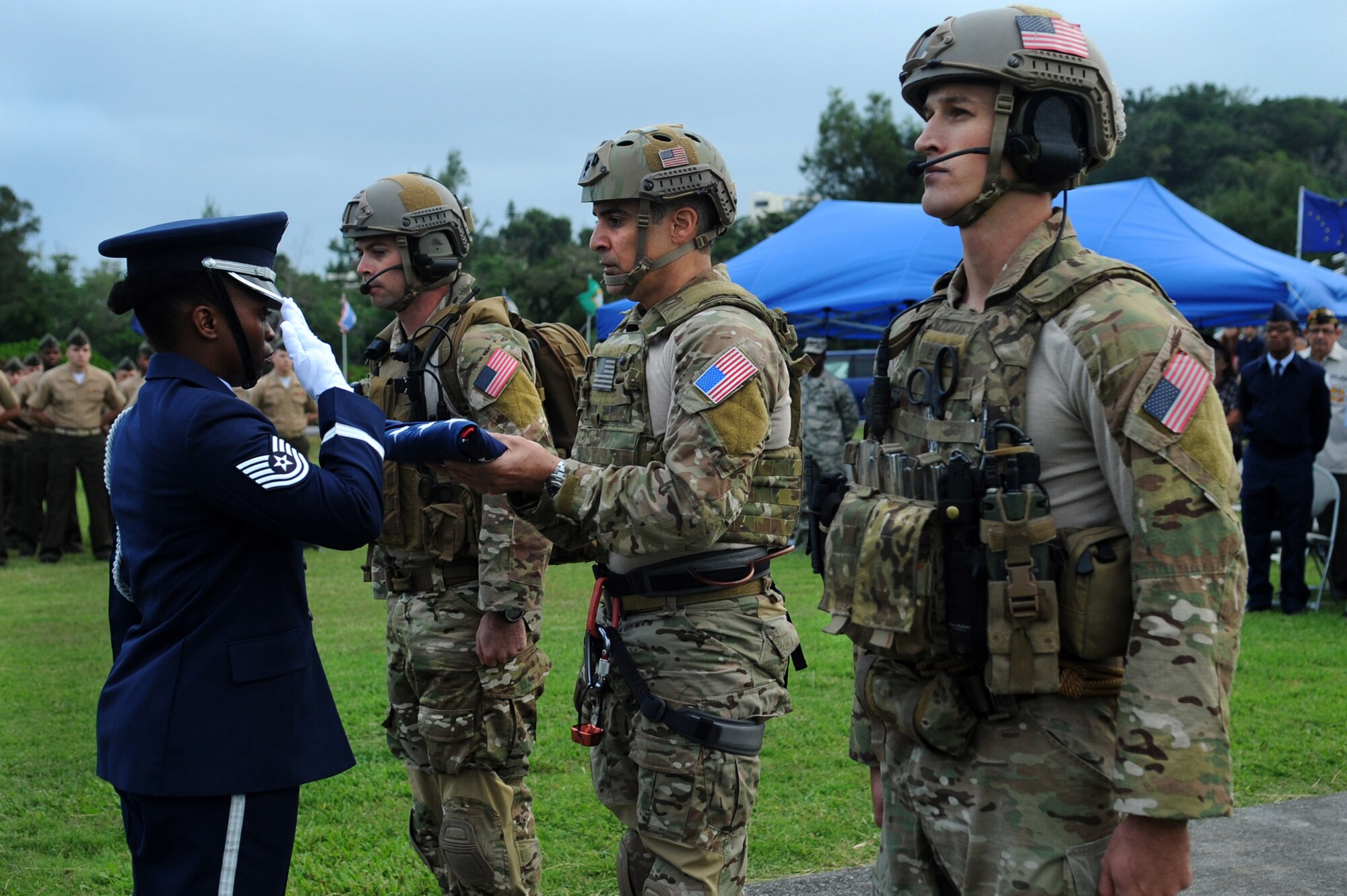 U.S. Air Force Chief Master Sgt. Ramon Colon-Lopez, 18th Wing command chief, presents the United States flag to a member of the Kadena Honor Guard with the assistance of Staff Sgt. George Reed (left) and Staff Sgt. Jordan St. Clair (right), both pararescuemen from the 31st Rescue Squadron, during a Veterans Day ceremony at Kadena Air Base, Japan, Nov. 11, 2013. As part of the Veterans Day ceremony, pararescuemen rappelled from an HH-60 Pave Hawk helicopter with the American flag. (U.S. Air Force photo by Staff Sgt. Amber E. N. Jacobs)