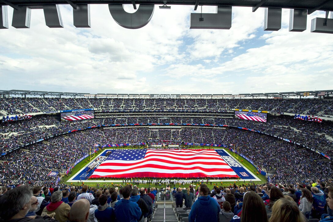 Service members, including Marines and sailors from amphibious assault ship USS New York, unfurl the American flag at MetLife Stadium before the football game between the New York Giants and Oakland Raiders in East Rutherford, N.J., Nov. 10, 2013.
