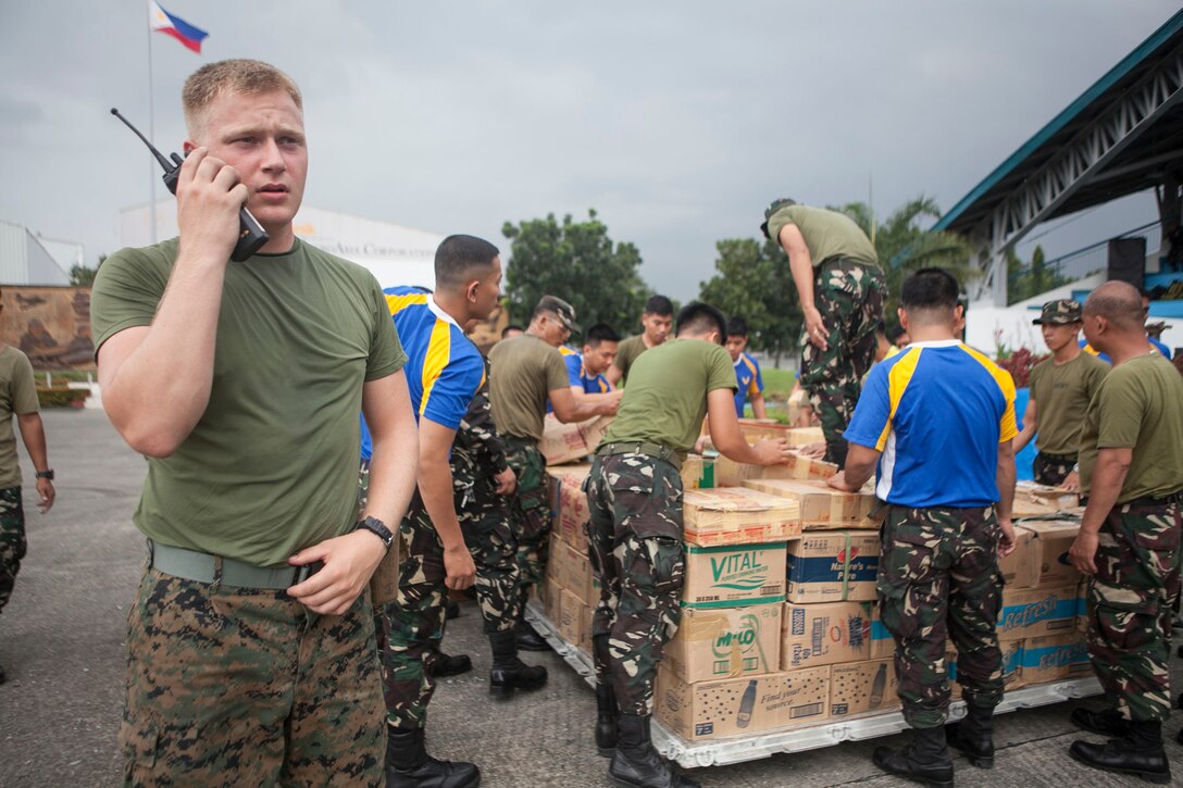 U.S. Marine Lance Cpl. Christopher E. Pring, a landing support specialist with Combat Logistics Regiment 3, currently assigned to 3d Marine Expeditionary Brigade, and a native of Tacoma, Wash., coordinates the loading of palletized water with the Philippine Air Force for transportation at Villamor Air Base, Nov. 12. Marines and sailors with 3d MEB are supporting the Philippine Armed Forces in providing humanitarian assistance and disaster relief to affected areas throughout the Republic of the Philippines following Typhoon Haiyan/Yolanda. (U.S. Marine Corps photo by Cpl. Codey Underwood)

