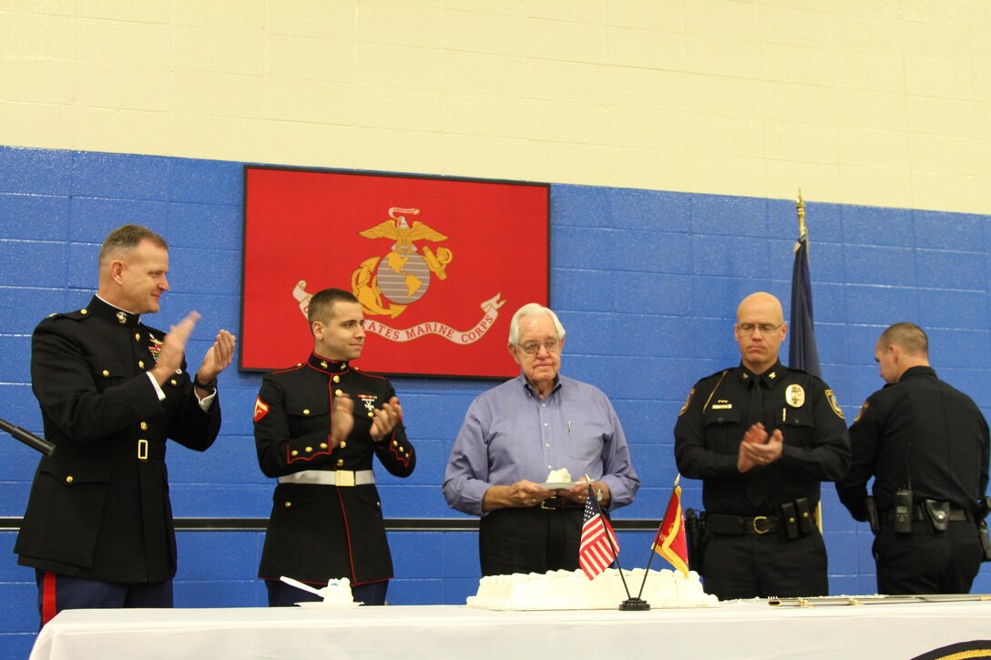 Col. James Minick commanding officer of the 9th Marine Corps District introduces Max Deweese the oldest Marine present and Lance Cpl. Bradley Carrier the youngest Marine present thier piece of birthday cake during the Lenexa Police Department birthday breakfast Nov. 8, 2013. This was the 19th year the Lenexa Police Department has held this event.