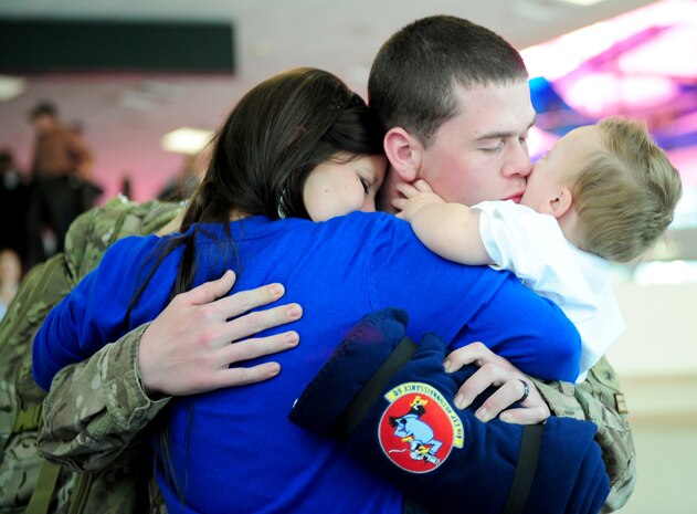 Senior Airman Joseph Tharp, 9th Operations Support Squadron flight equipment technician, kisses his son Liam and embraces his wife Sarah Nov. 7, 2013, at Sacramento International Airport. Tharp was returning home from a deployment to Afghanistan. (U.S. Air Force photo by Airman 1st Class Bobby Cummings/Released)