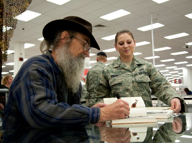 Tech. Sgt. Jessica Brede, 547th Intelligence Squadron intelligence analyst, assists Si Robertson during his book signing appearance at the Exchange Nov. 12, 2013, at Nellis Air Force Base, Nev. Robertson autographed copies of his book, “Si-cology 1: Tales and Wisdom from Duck Dynasty’s Favorite Uncle” and met with more than 1,200 fans from the Nellis AFB community. (U.S. Air Force photo by Master Sgt. Jason W. Edwards)