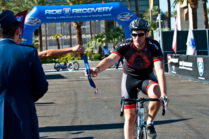 Staff Sgt. Brent Olson, 99th Ground Combat Training Squadron military working dog instructor, completes the honor ride and grabs a medal during the Ride 2 Recovery Honor Ride Nov. 9, 2013, on the Las Vegas strip. The Honor Ride hosted more than 500 riders to cycle a 39-mile course. (U.S. Air Force photo by Senior Airman Brett Clashman)