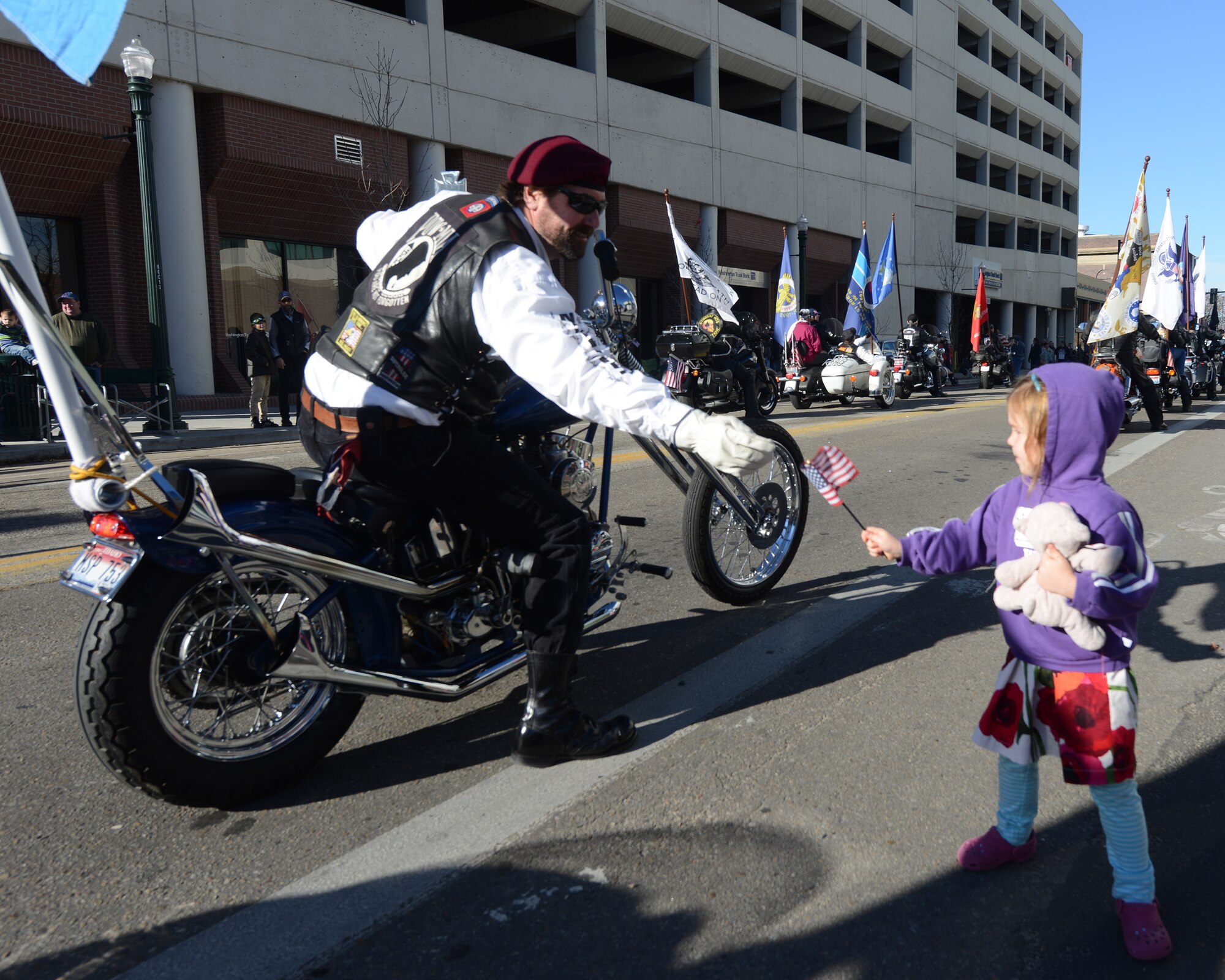 A member of the Prisoner of War Missing in Action motorcycle group hands a flag to a little girl Nov.9, 2013, in Boise, Idaho. More than 10 veteran motorcycle groups joined together to ride in the Boise Veterans Day parade.(U.S.
Air Force photo by Airman 1st Class Brittany A. Chase/Released)
