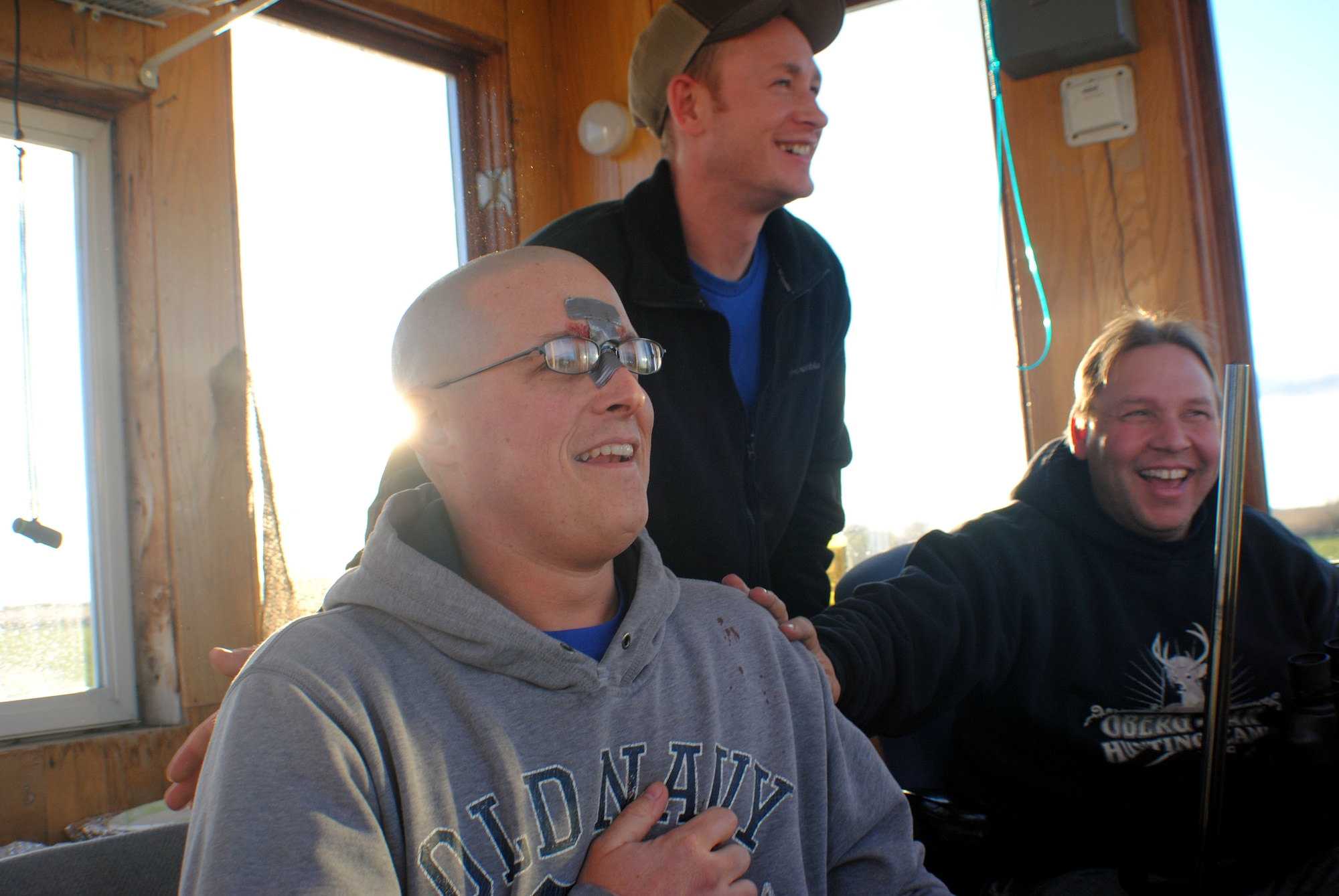 (From right to left) Retired Air Force Maj. James Oberg, and Master Sgt. Keelan Rasmusson congratulate Tech. Sgt. Joshua Robistow, an active-duty Wounded Warrior  from the 319th Civil Engineer Squadron, who successfully shot a six-point buck during his first white tail deer hunt Nov. 11, 2013, on a farm just a few miles from the town of Warren, Minn. The gray duct tape on Robistow’s nose was used as a temporary bandage to cover a cut made when he positioned his face too close to the scope of a .330 caliber rifle he fired during his first attempt at shooting another buck earlier in the day. Robistow playfully said he thought it was both funny and coincidental that he got another wound being a Wounded Warrior. (U.S. Air Force photo/Staff Sgt. Luis Loza Gutierrez) 