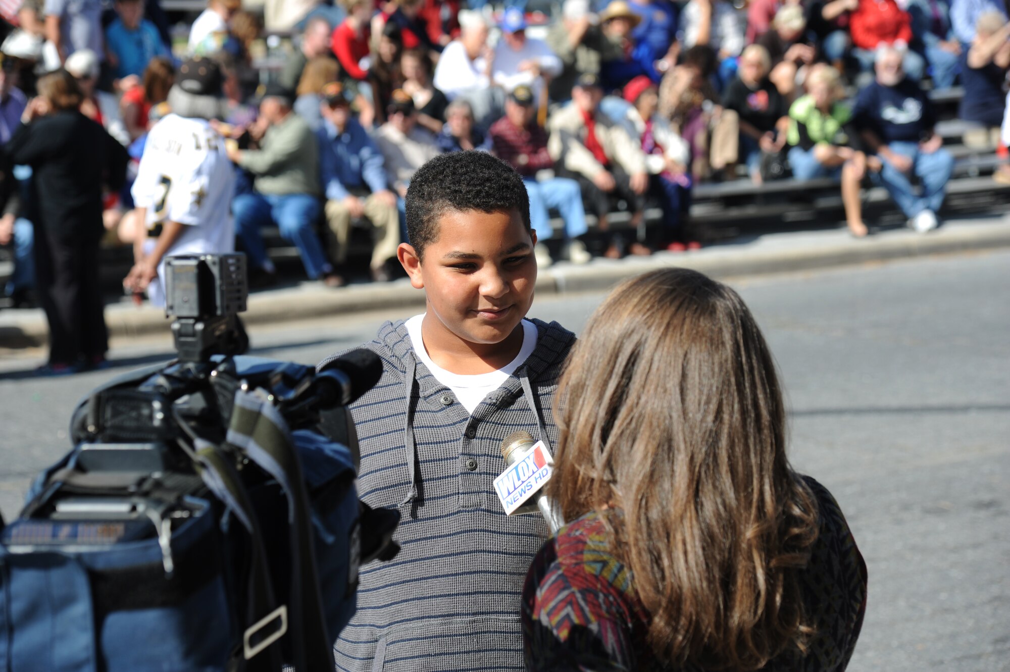 The son of Chief Master Sgt. Farrell Thomas, 81st Training Wing command Chief, and Senior Master Sgt. Lisa Thomas, 81st Force Support Squadron, is interviewed by Caray Grace, WLOX News reporter, during the 13th Annual Gulf Coast Veterans Day Parade in front of City Hall Nov. 9, 2013, Biloxi, Miss. Keesler’s Wing leadership, Honor Guard, and Airmen, who carried the 50 State Flags, participated in the event.  (U.S. Air Force photo by Kemberly Groue)