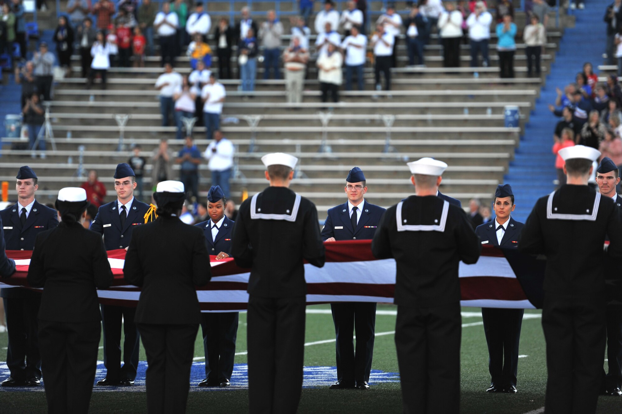 SAN ANGELO, Texas-- Team Goodfellow service members hold a 38 foot American Flag during the Angelo State University Military Appreciation Day football game halftime performance Nov. 9 at the LeGrand Stadium. Hundreds of service members and veterans came to the football game to see the ASU Rams face off against Texas A&M- Kingsville, which featured free admission for active duty military members. (U.S. Air Force photo/ Senior Airman Michael Smith)